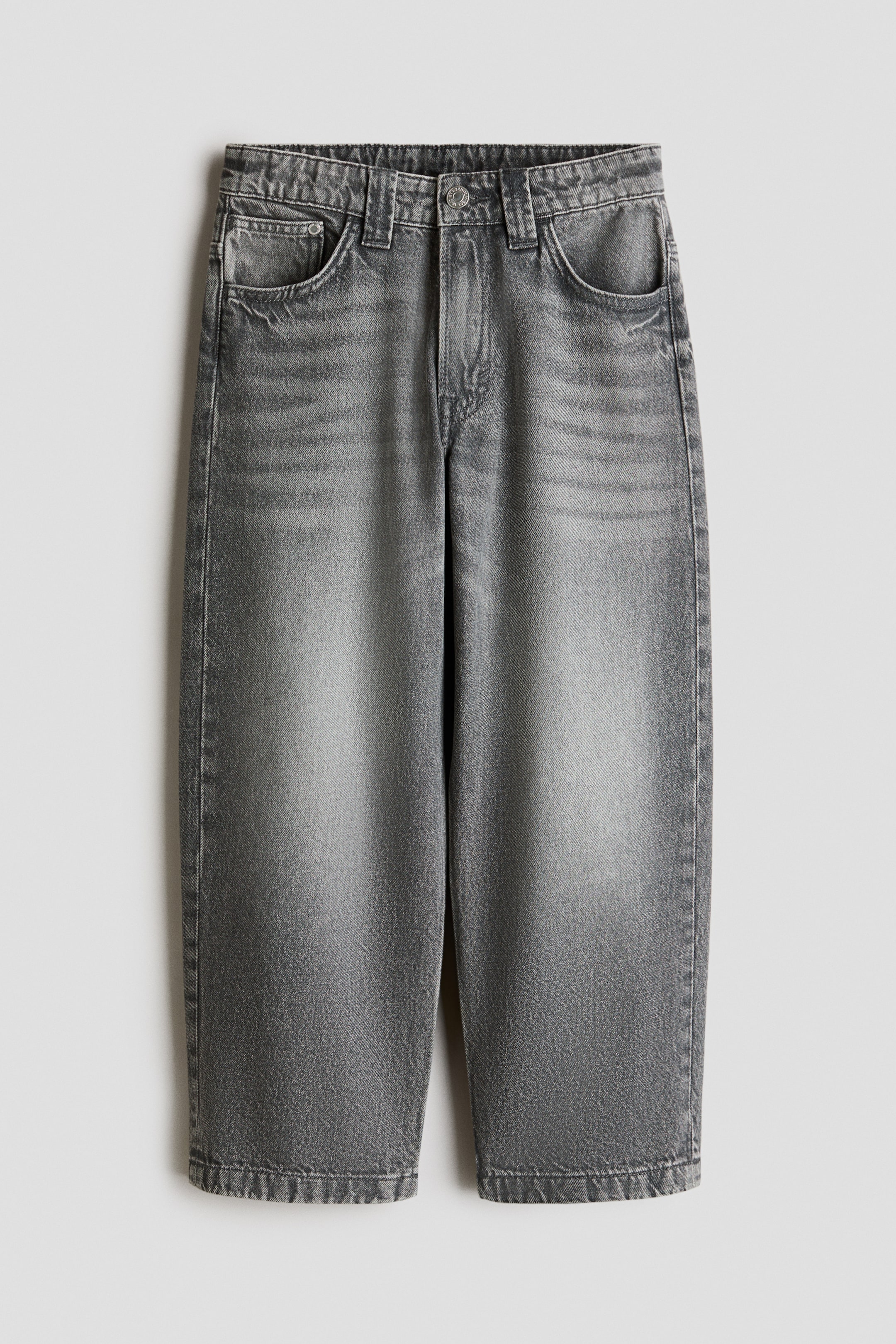 View larger image: These grey washed denim jeans feature a loose fit through the hip and thigh, a dropped crotch, and wider legs. They are designed with a 5-pocket style, a zip fly, and a visible button fastening at the waistband.