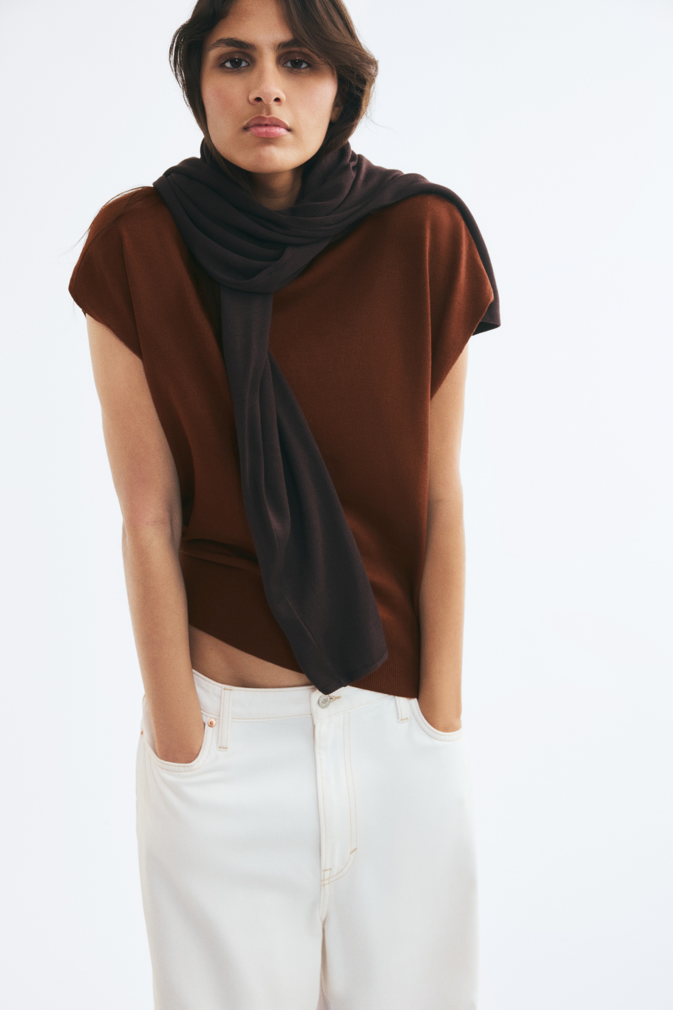 A brown fine-knit sleeveless top featuring a mock neck and a ribbed hem, presented front-facing.