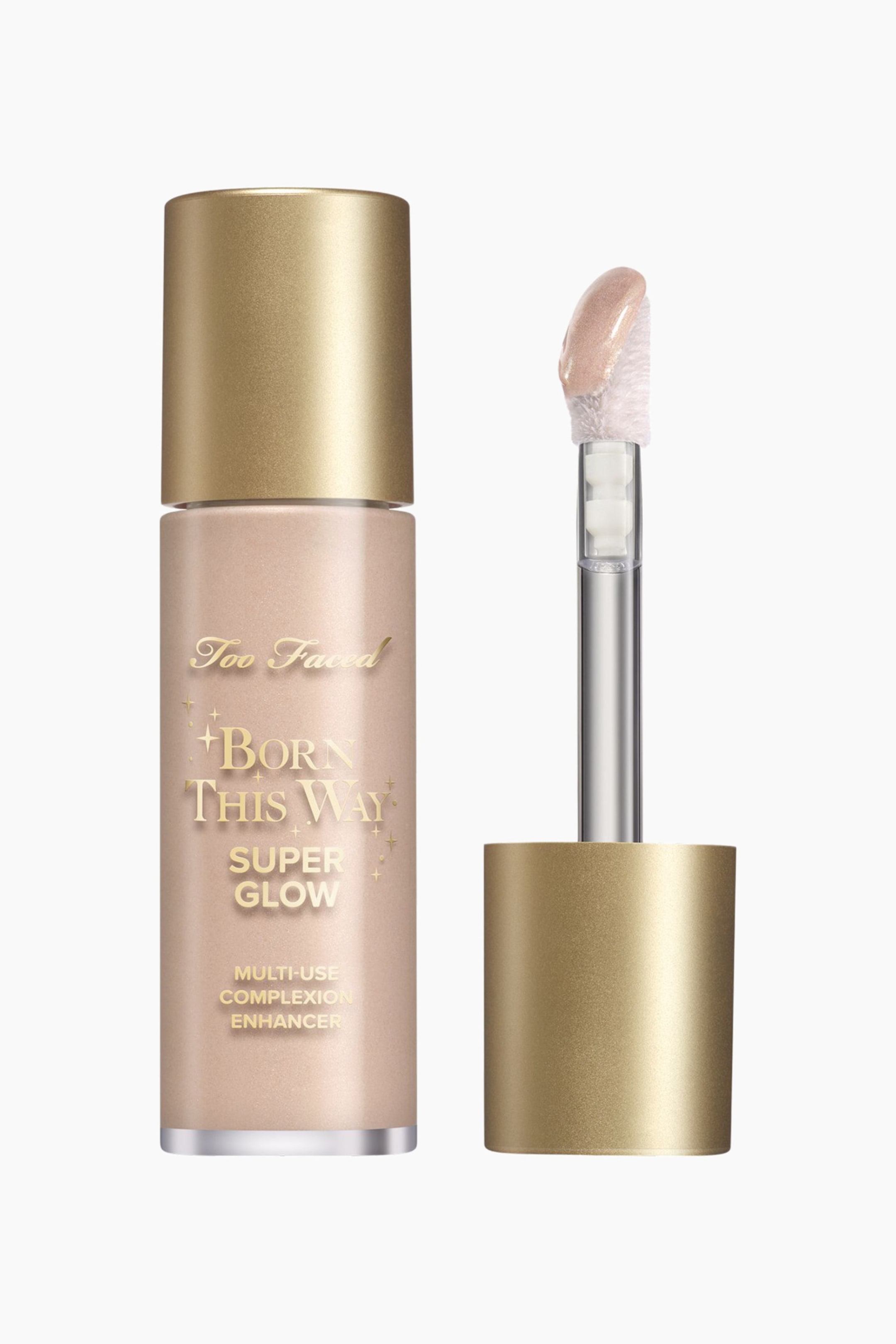 Visa större bild: En Too Faced Born This Way Super Glow Multi-Use Complexion Enhancer är en ljusbeige cylindrisk flaska med metalliskt guldskrift och ett guldfärgat lock, stående upprätt. En separat applikator med en doe-foot, som innehåller en skimrande ljusbeige produkt, står också upprätt bredvid flaskan.
