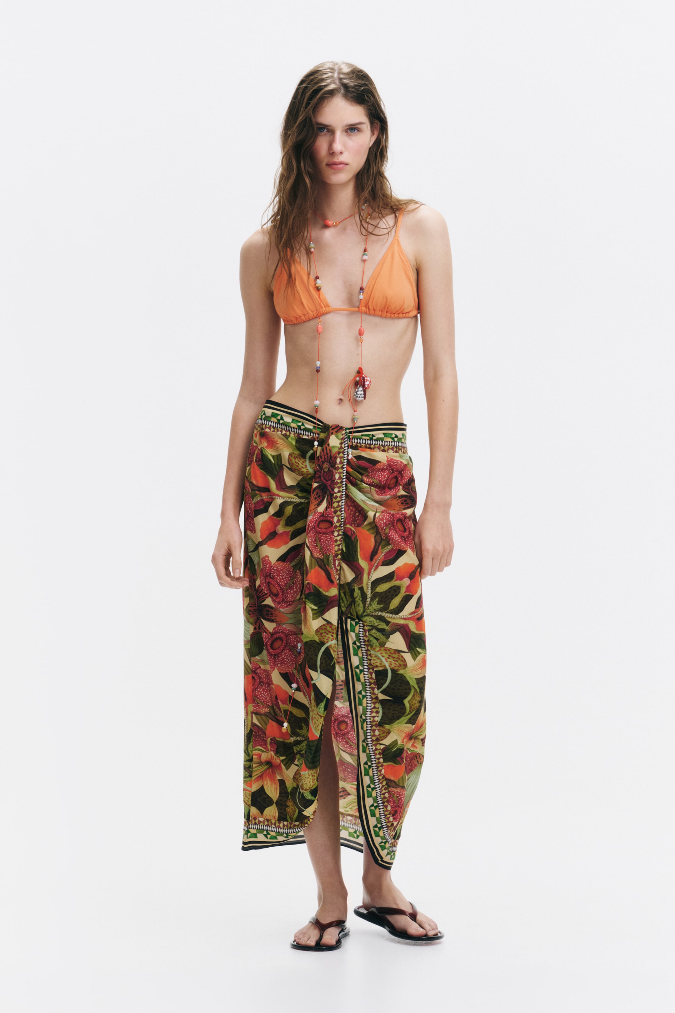 View larger image: The model is wearing a calf-length skirt made from lightweight viscose, showcasing a tropical floral and leaf print with a draped front detail.