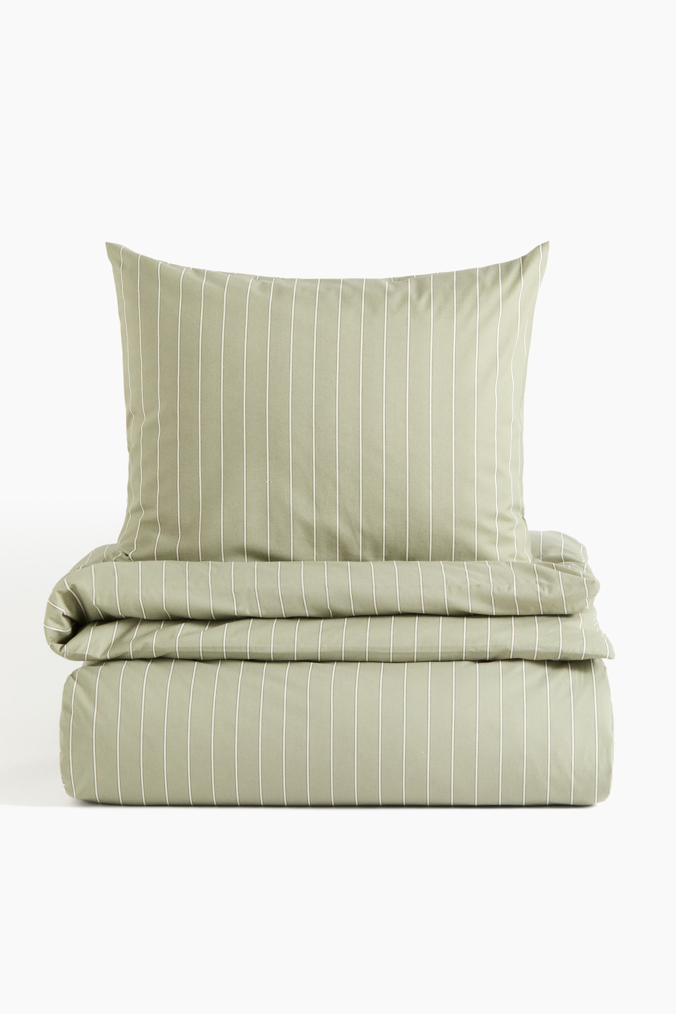 View larger image: A sage green bedding set showcases a pillow standing upright behind a horizontally folded duvet cover, both items featuring vertical white stripes.