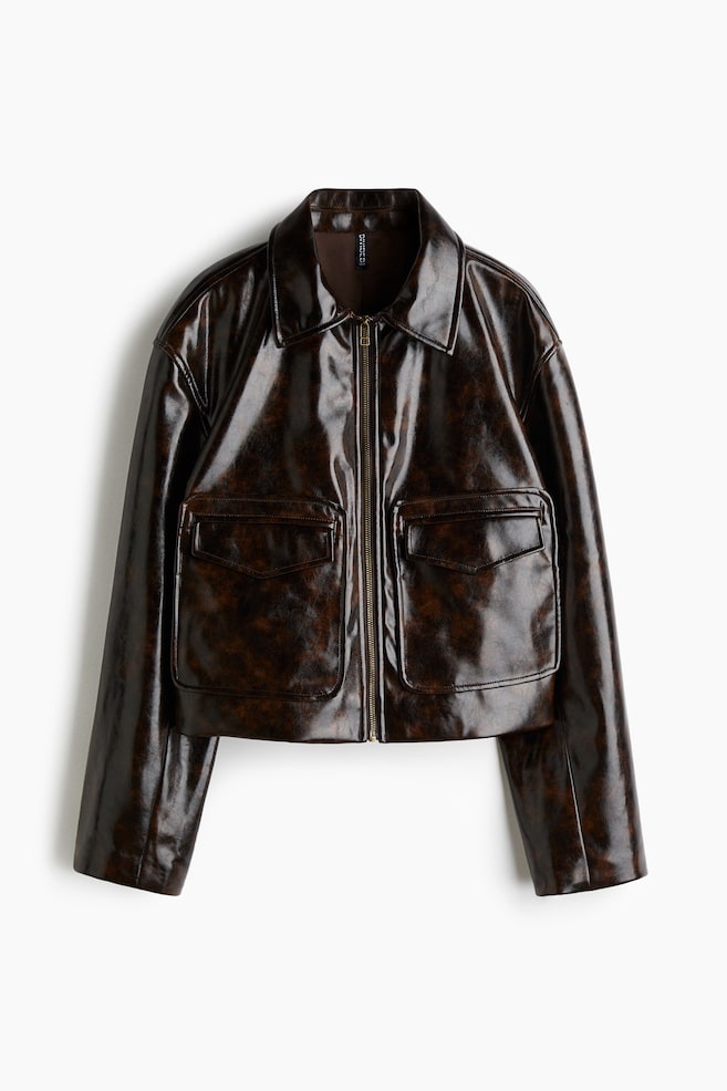 A jacket in mottled dark brown with a high-gloss finish is presented frontally. It is featuring a spread collar, a full-length center front zipper, and two large patch pockets with pointed flaps on the lower front. - 1