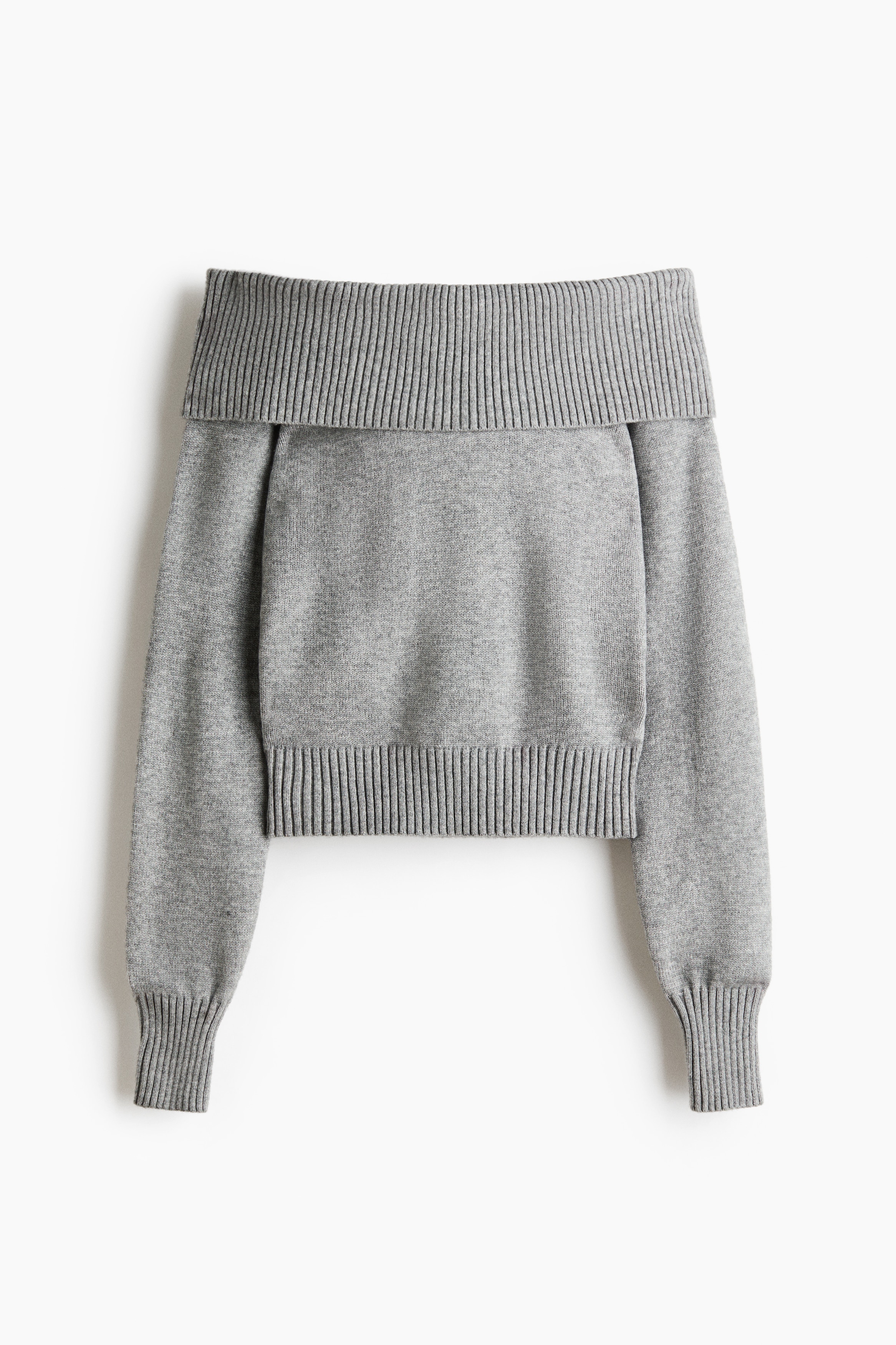 Een off-shoulder trui van zachte grijze knit wordt gedragen door het model, met een brede, geribbelde omgeslagen halslijn en lange mouwen met geribbelde manchetten. De trui is gestyled met een dunne, roze en grijs gestreepte sjaal die losjes om de hals is gedrapeerd en is ingestopt in lichtgrijze bottoms met trekkoord.