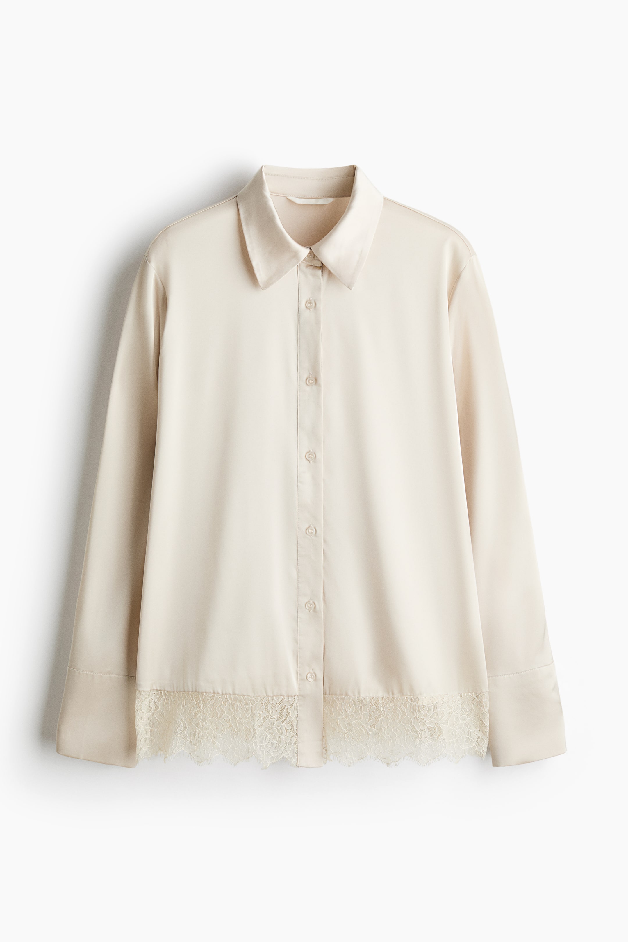View larger image: A cream-coloured, long-sleeved satin shirt is shown from the front, featuring a classic point collar, a central button-down placket, and wide cuffs. The straight-cut shirt is detailed with a delicate, semi-sheer floral lace trim along the bottom hem.