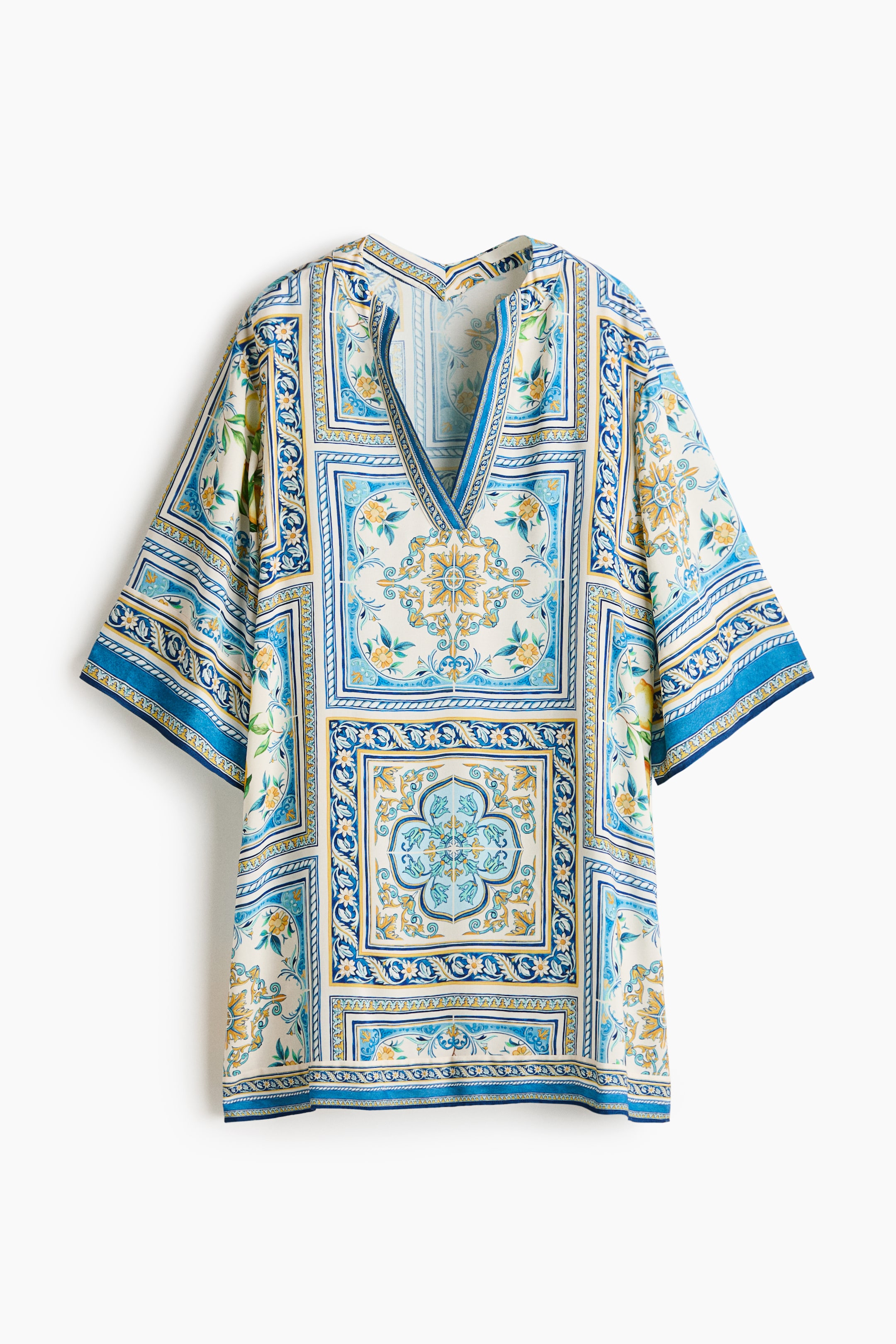Agrandir l'image: Une robe tunique courte et oversize en tissage de viscose est présentée à l'avant, avec un décolleté en V à l'avant et à l'arrière, des épaules tombantes et des manches 3/4. Elle affiche un motif complexe de carrés bleus, blancs et jaunes avec des motifs floraux et géométriques.