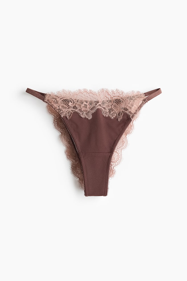 A dark brown thong features a front panel with narrow side straps. It is adorned with light pink floral lace along the waistline, extending down to the scalloped leg openings. - 1