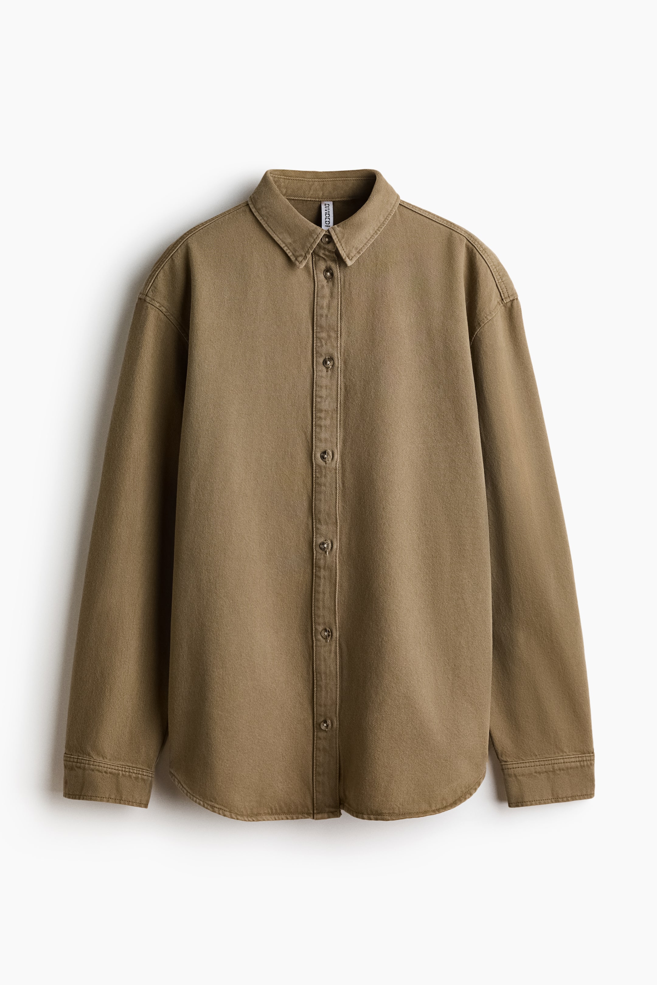 View larger image: An oversized khaki denim shirt is showcasing its front, highlighting a collar and a buttoned placket running down the center. It features dropped shoulders, long sleeves with buttoned cuffs, and a rounded hem.