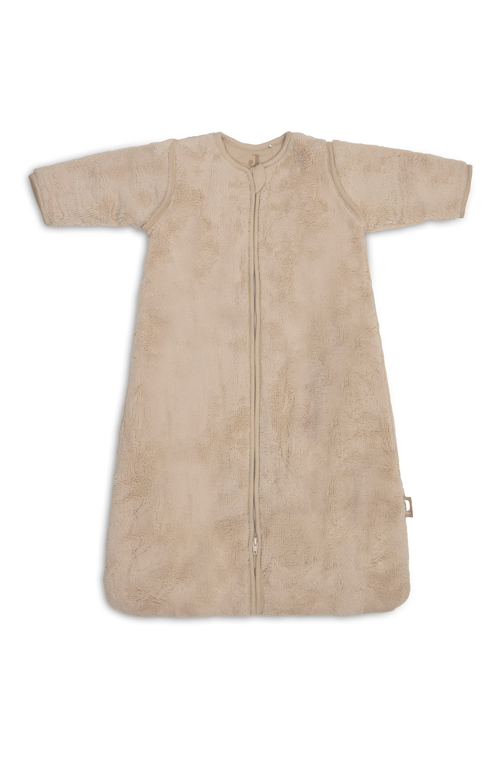 Ein beigefarbener, kuscheliger Fleece-Babyschlafsack hÃ¤ngt frontal auf einem HolzstÃ¤nder und verfÃ¼gt Ã¼ber einen durchgehenden FrontreiÃverschluss sowie lange, abnehmbare Ãrmel, die an den SchulternÃ¤hten mit ReiÃverschlÃ¼ssen befestigt sind. Ein kleines PlÃ¼schschaf mit einem Holzring hÃ¤ngt am AufhÃ¤ngehaken direkt Ã¼ber dem Kragen.