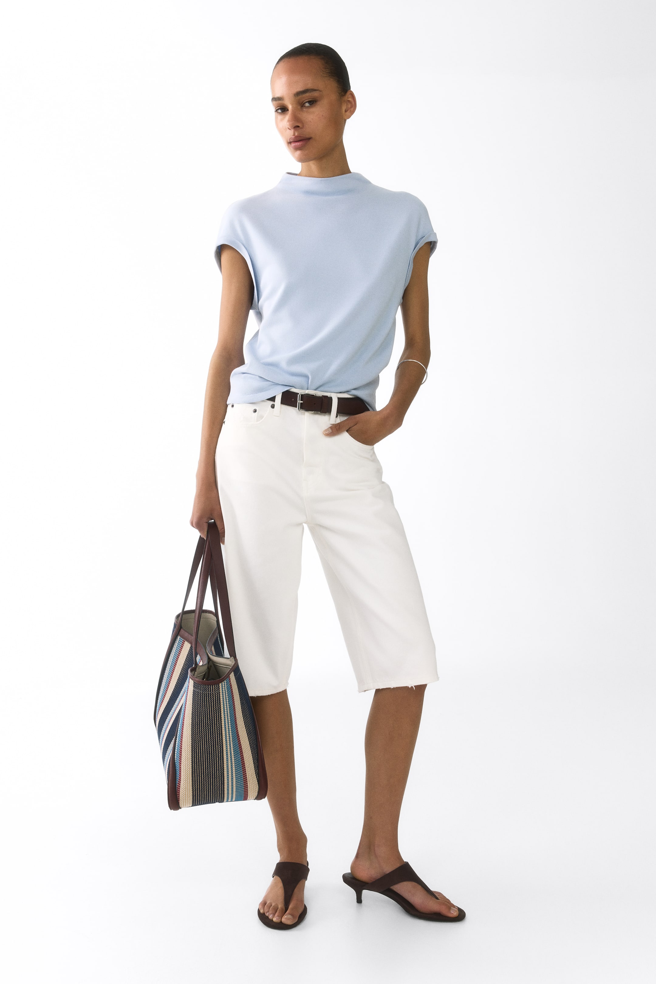View larger image: A light blue top featuring a mock neck and short cap sleeves, offering a relaxed fit when tucked into white shorts.