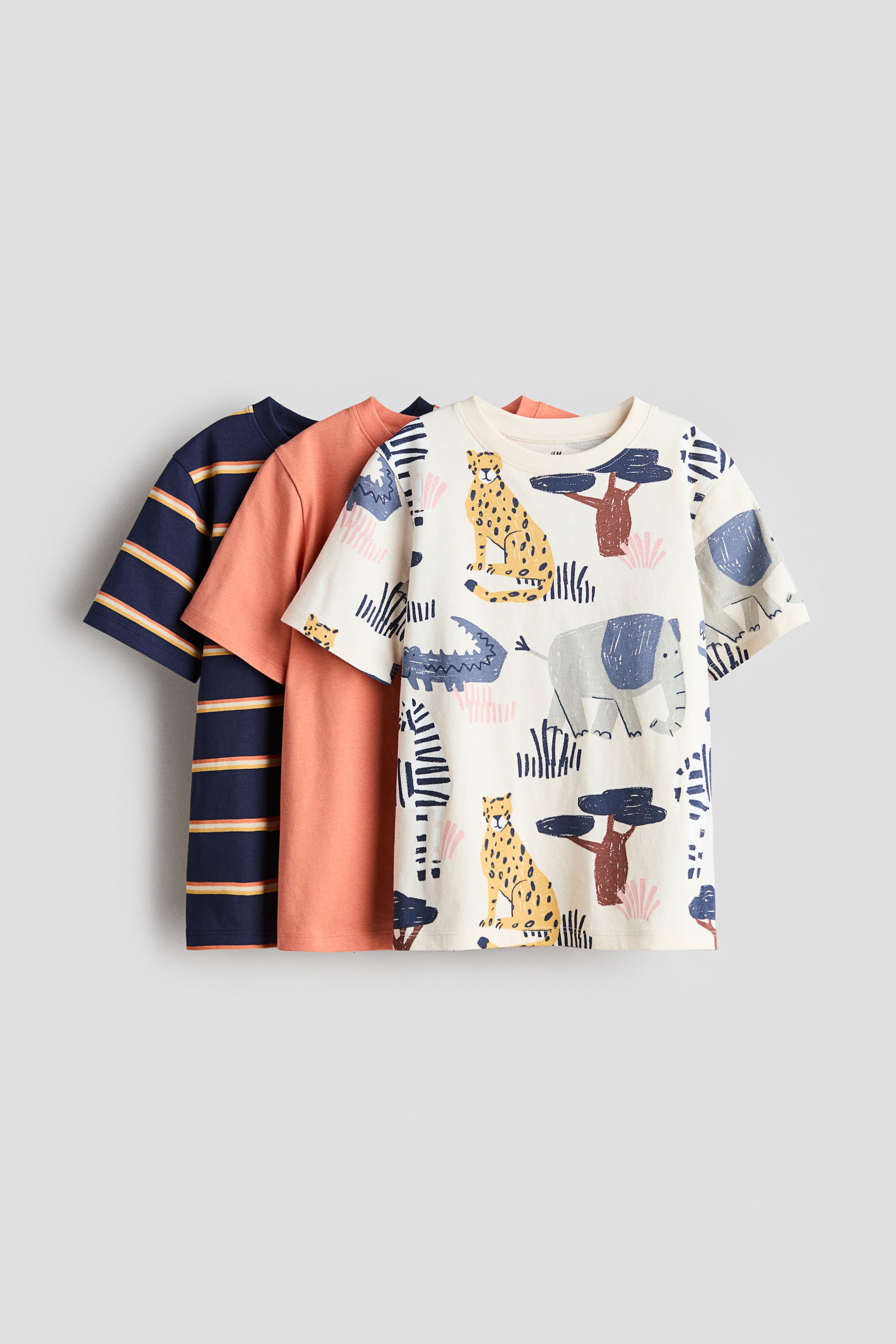 View larger image: The product is a set of three t-shirts, showcased in a layered front view. The foremost t-shirt exhibits a cream base with an animal print, while the middle t-shirt is a solid coral hue, and the backmost t-shirt features a navy blue with horizontal stripes. All t-shirts come with ribbed trims around their necklines and gently dropped shoulders.