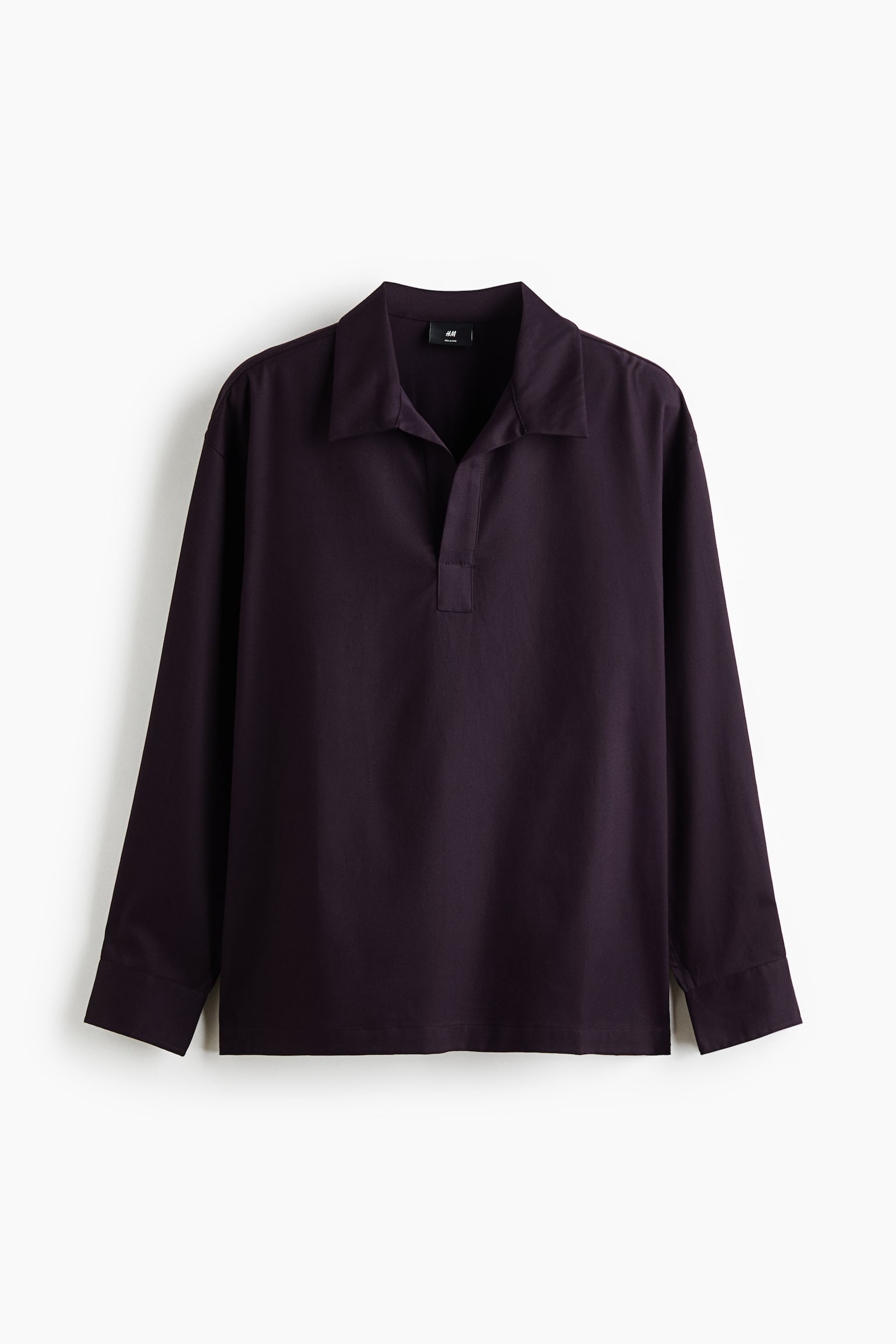 A dark purple long-sleeved polo-style shirt is shown from the front, featuring a relaxed fit with a classic open collar and a buttonless placket. The shirt has long sleeves with wide cuffs and a straight hemline.