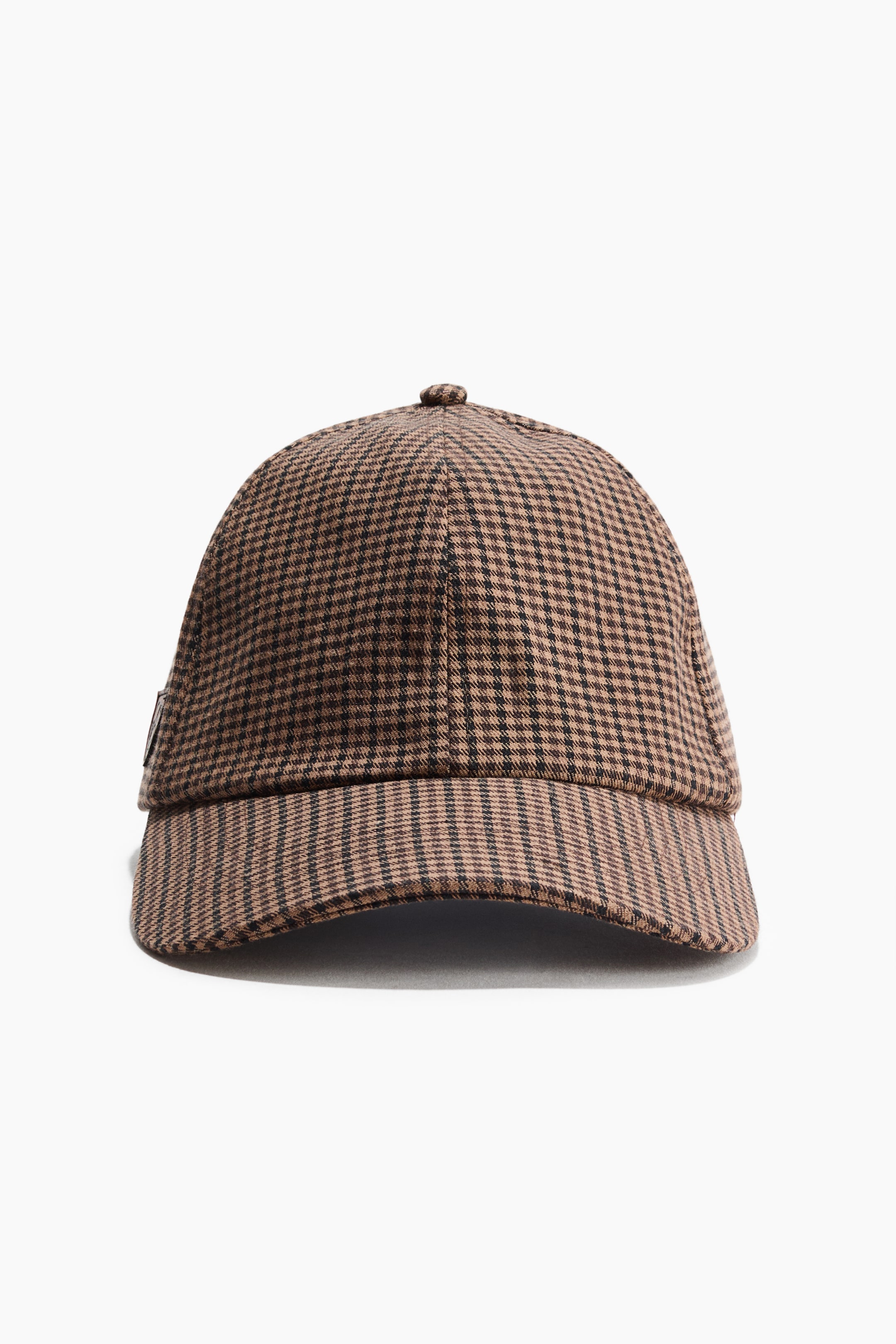 View larger image: A cap is shown from the front, featuring a small brown-and-black check pattern on its cotton twill fabric. It is designed with a curved brim and a button on top of the crown.