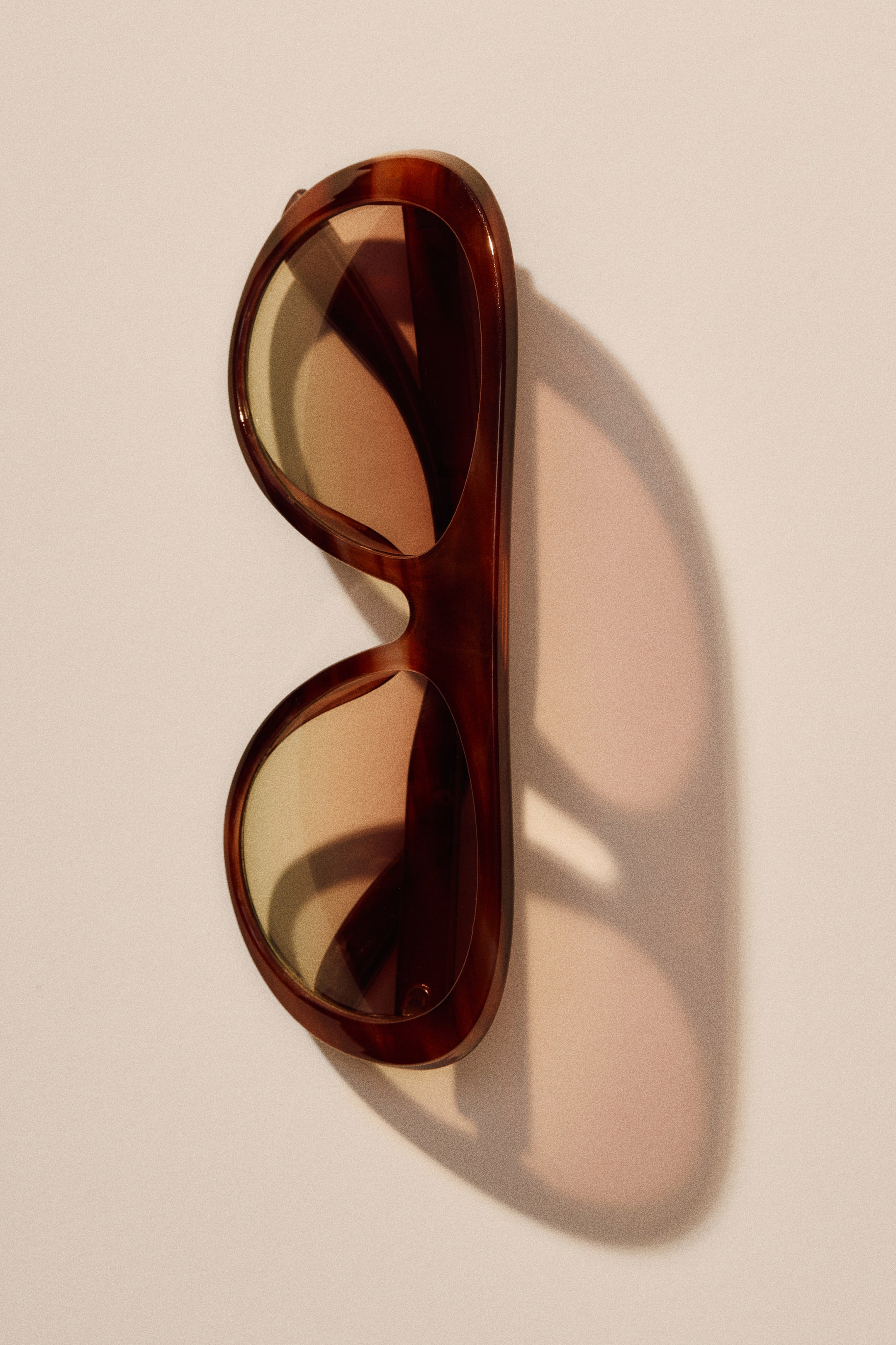 View larger image: Aviator-style sunglasses feature tortoiseshell plastic frames and amber-tinted, UV-protective lenses. The front view highlights the distinct lens shape and integrated bridge design.