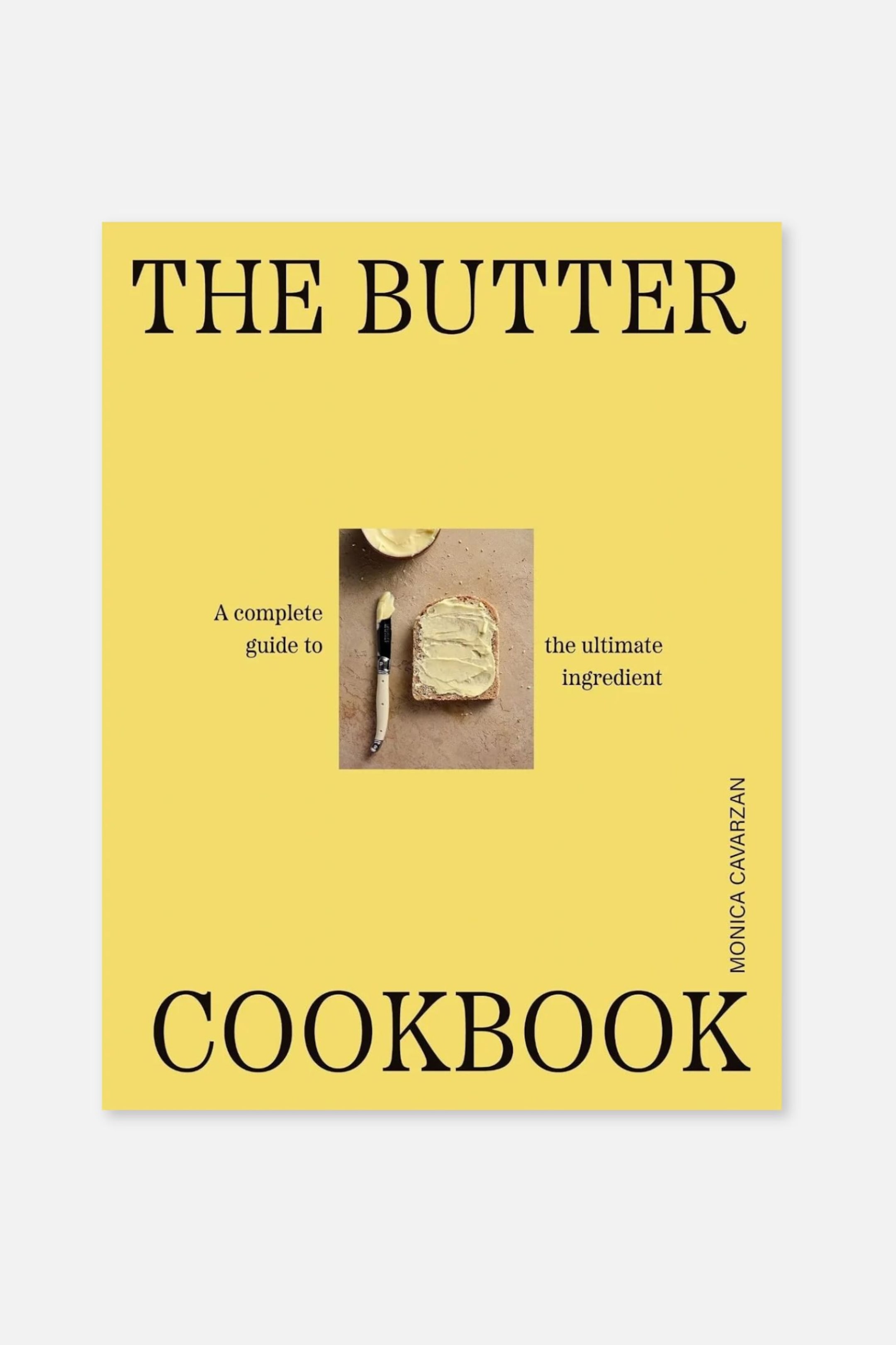 Größeres Bild anzeigen: Das Kochbuch mit dem Titel „THE BUTTER COOKBOOK“ zeigt einen leuchtend gelben Einband mit großem schwarzem Serifenschriftzug oben und unten. In der Mitte ist ein kleines Foto zu sehen, das eine Brotscheibe mit aufgestrichener Butter neben einem Messer zeigt, eingerahmt von den Worten „A complete guide to“ und „the ultimate ingredient“. Der Name der Autorin, „MONICA CAVARZAN“, verläuft vertikal am unteren rechten Rand.