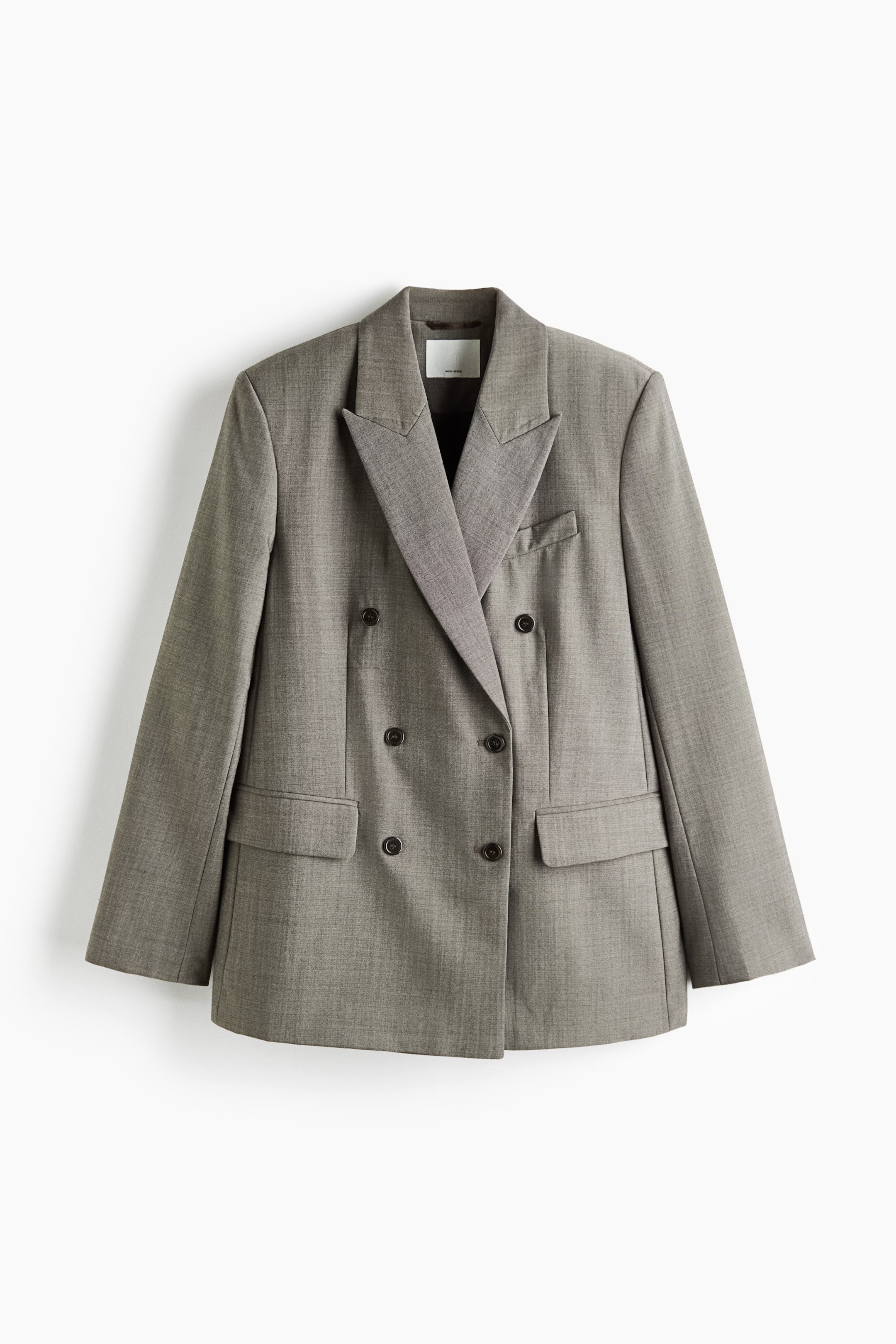 Agrandir l'image: Un blazer gris à double boutonnage est présenté de face, avec de larges revers en pointe et une fermeture à six boutons. Le blazer présente des épaules structurées, une poche poitrine passepoilée unique et deux poches à rabat inférieures, le tout confectionné dans un tissu gris chiné texturé.