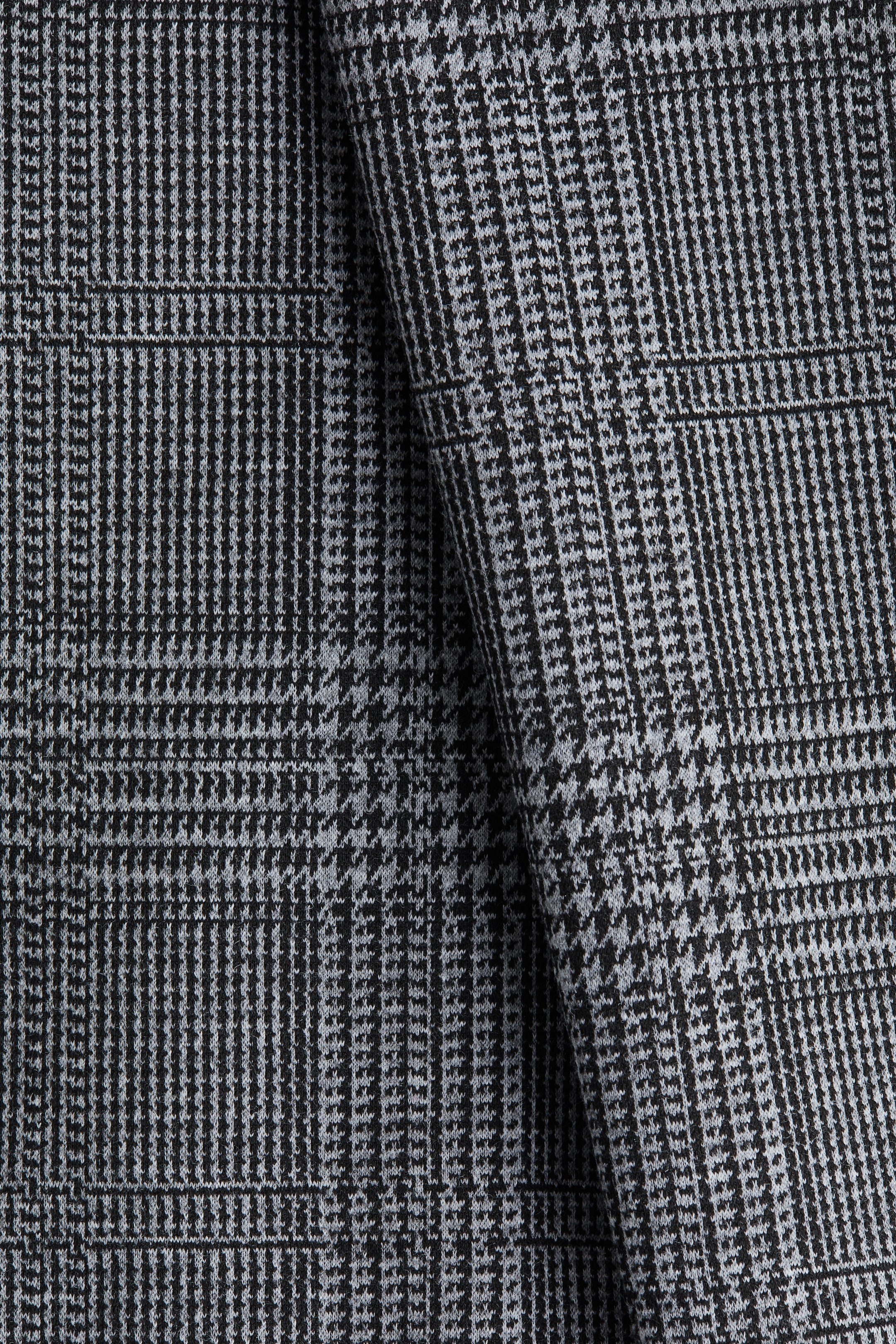 Xem ảnh lớn hơn: Một loại vải dệt màu đen và xám nhạt đang trưng bày một họa tiết Glen Plaid chi tiết. Vải được gấp nhẹ nhàng, làm nổi bật thiết kế kẻ ô phức tạp của nó.