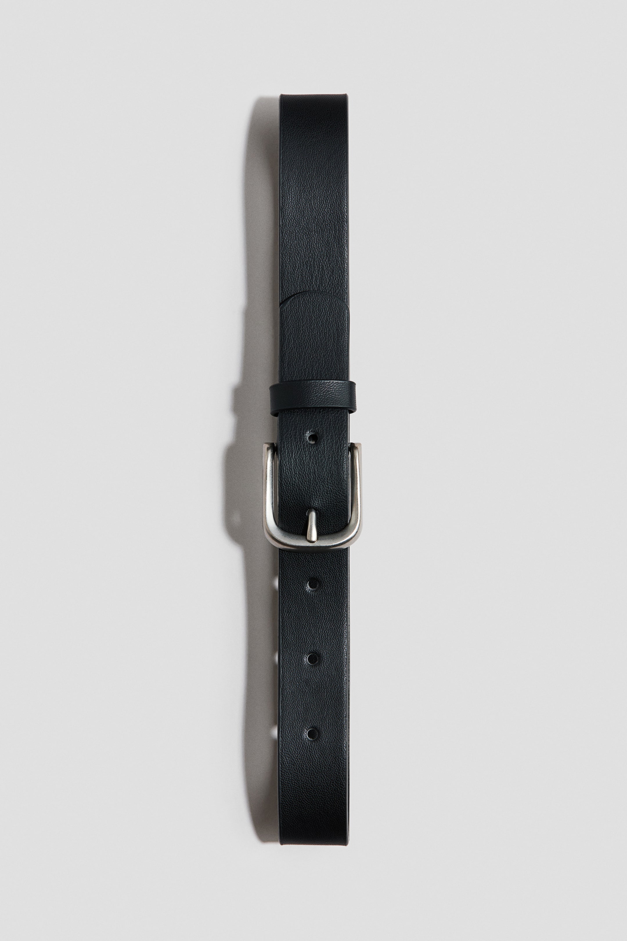 Grotere afbeelding bekijken: Een zwarte riem van gecoate stof ligt plat, met de voorkant zichtbaar, voorzien van een zilverkleurige metalen gesp, meerdere verstelgaten en een enkele lus.