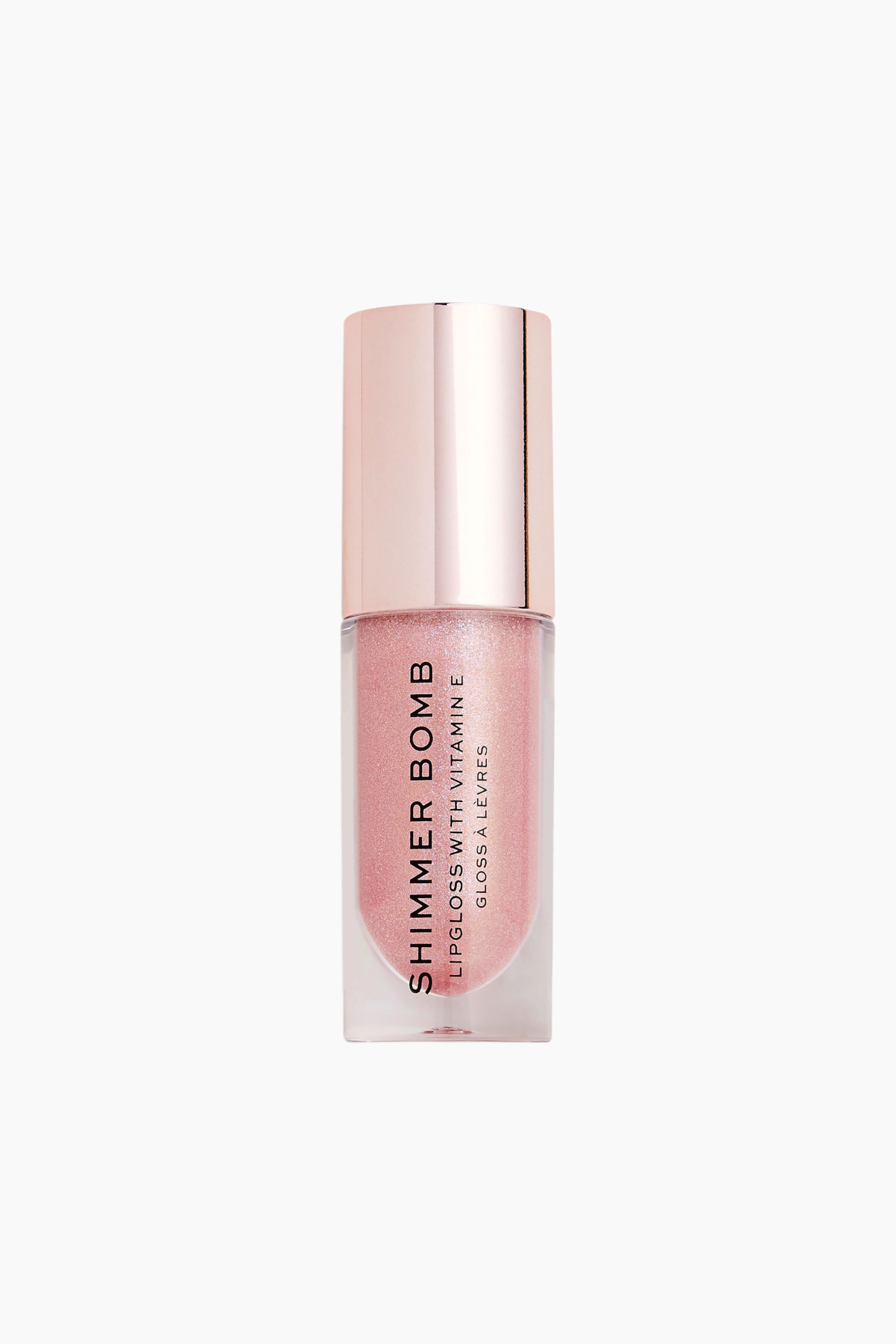 Größeres Bild ansehen: Eine Tube Revolution Shimmer Bomb Lipgloss steht aufrecht und präsentiert eine klare, rechteckige Flasche, die mit einem schimmernden, hellrosa Gloss gefüllt ist. Auf der Vorderseite ist vertikaler schwarzer Text zu sehen, und sie verfügt über einen zylindrischen, metallischen roségoldenen Deckel.