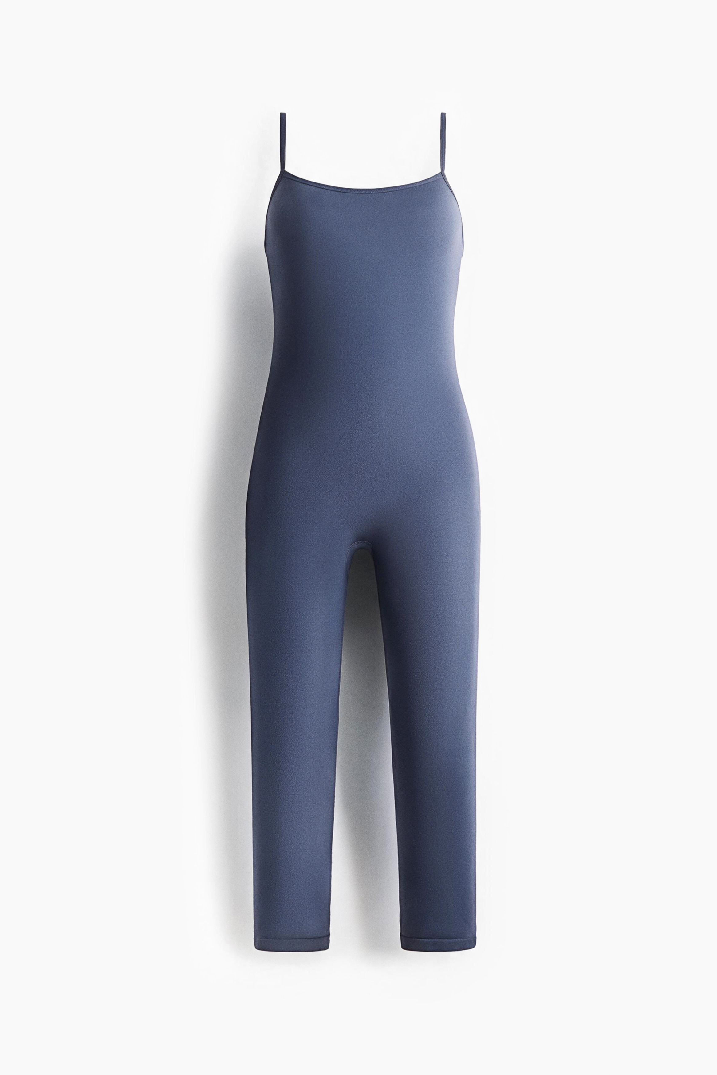 A blue stretch jersey unitard featuring a straight neckline and narrow shoulder straps is being worn by the model. The model is holding a matching fuzzy knit sweater draped around the waist.