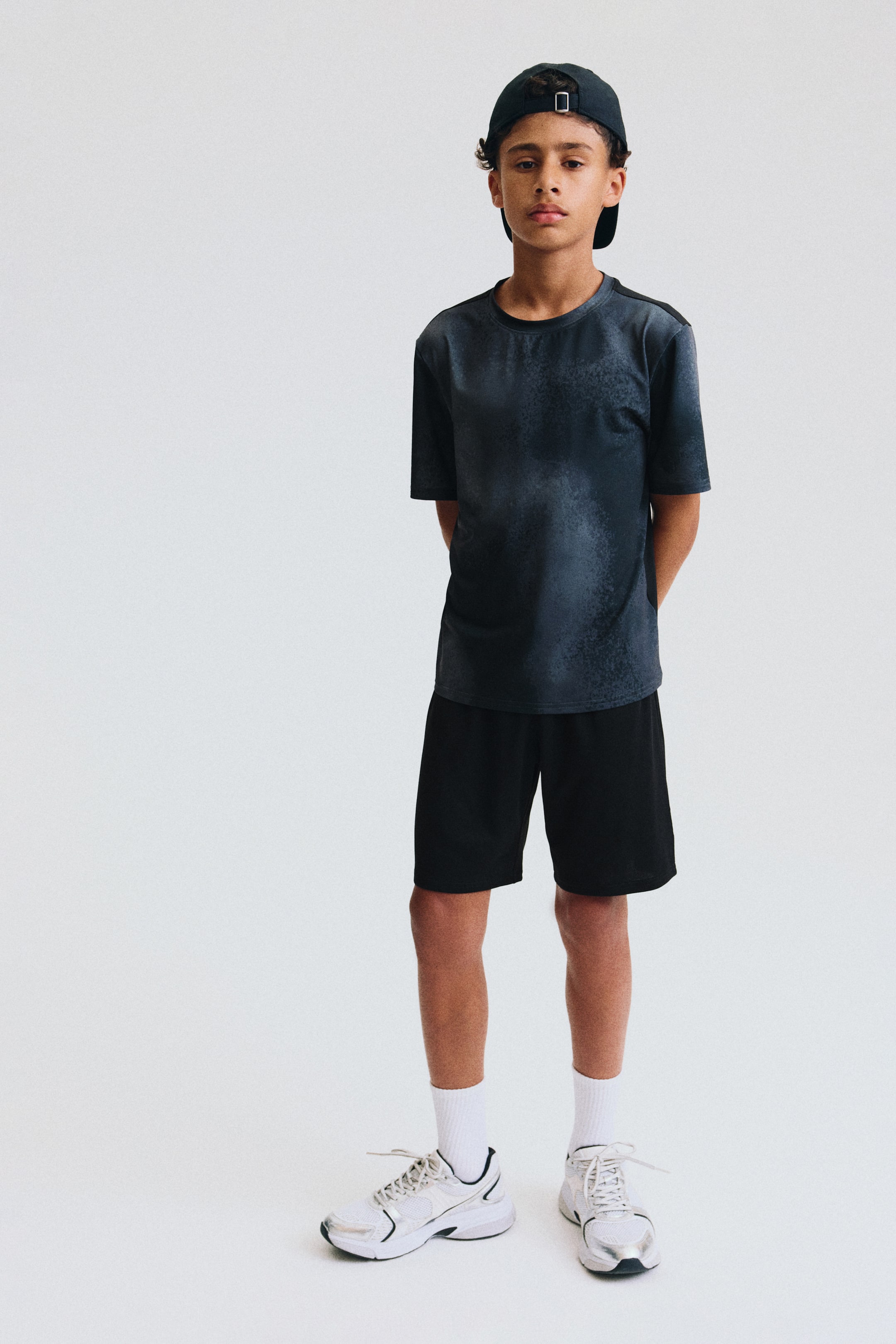 View larger image: A dark gray t-shirt with a subtle mottled pattern is showcased from the front, featuring short sleeves and a crew neck. Black athletic shorts are also showcased, reaching just above the knees.