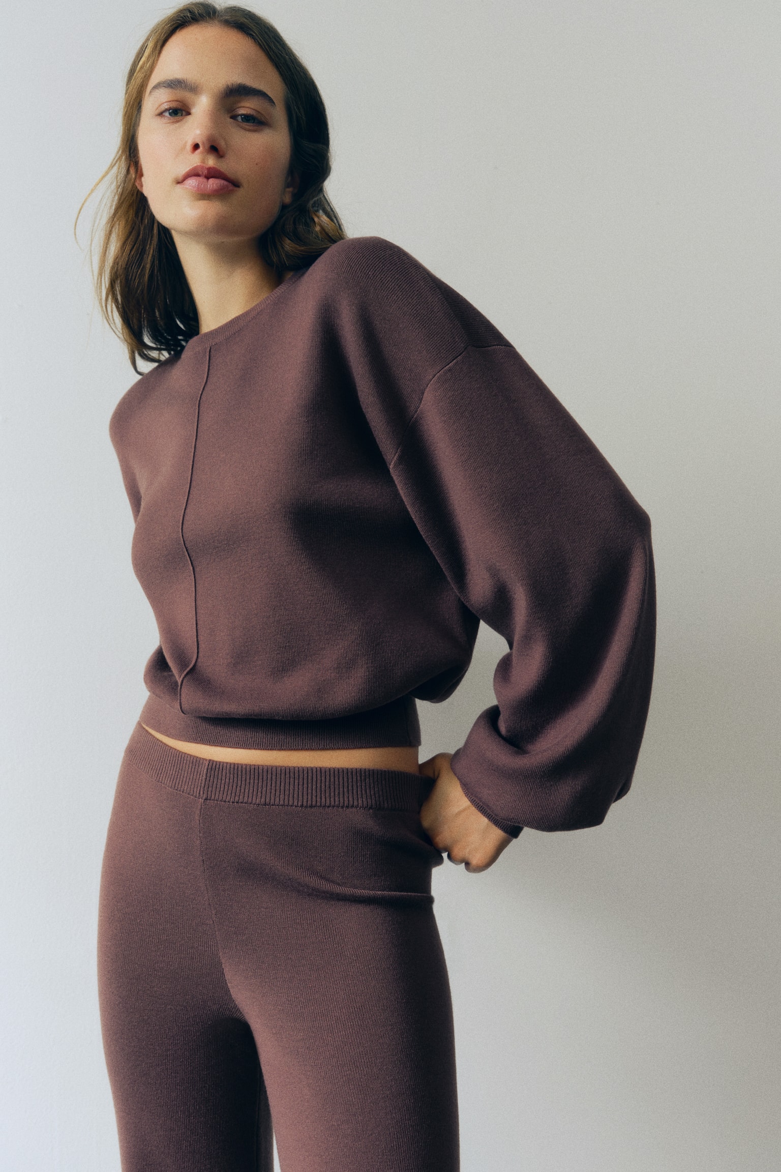 A dark brown jumper featuring a ribbed crew neck, voluminous long sleeves with ribbed cuffs, and a ribbed, gathered hem. A vertical seam runs down the centre front. - 1