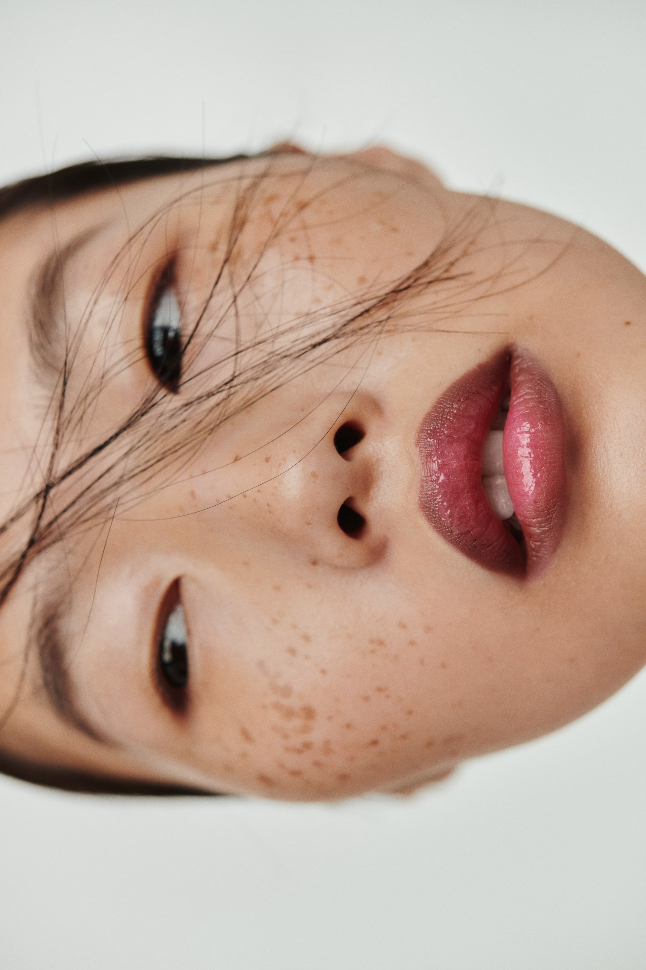 View larger image: A glossy berry-toned lip color graces full, slightly parted lips, showcasing a high-shine finish from a close-up, angled view.