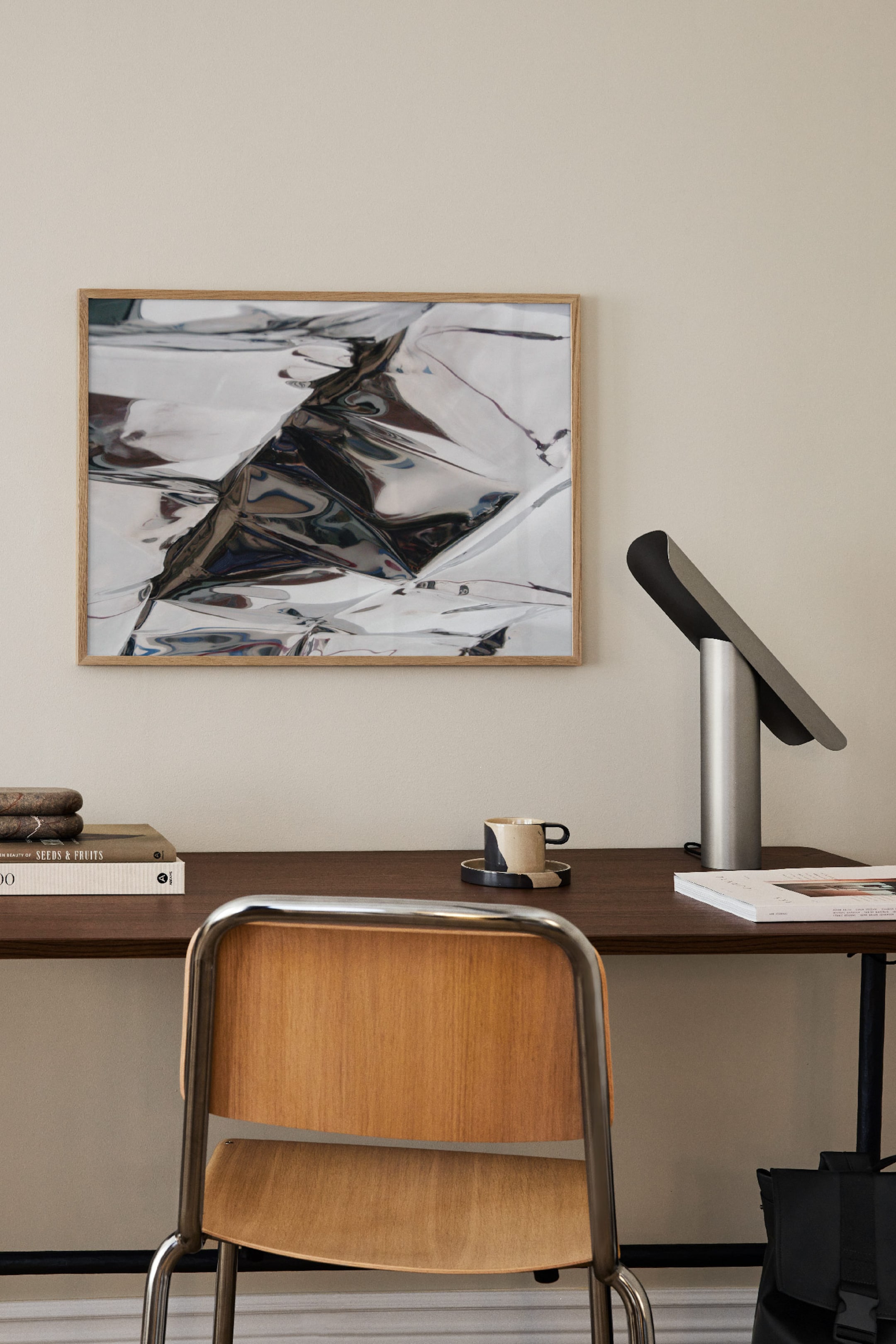 View larger image: The framed artwork is displaying a rectangular image of crumpled, reflective silver material, enclosed in a thin, light wooden frame.