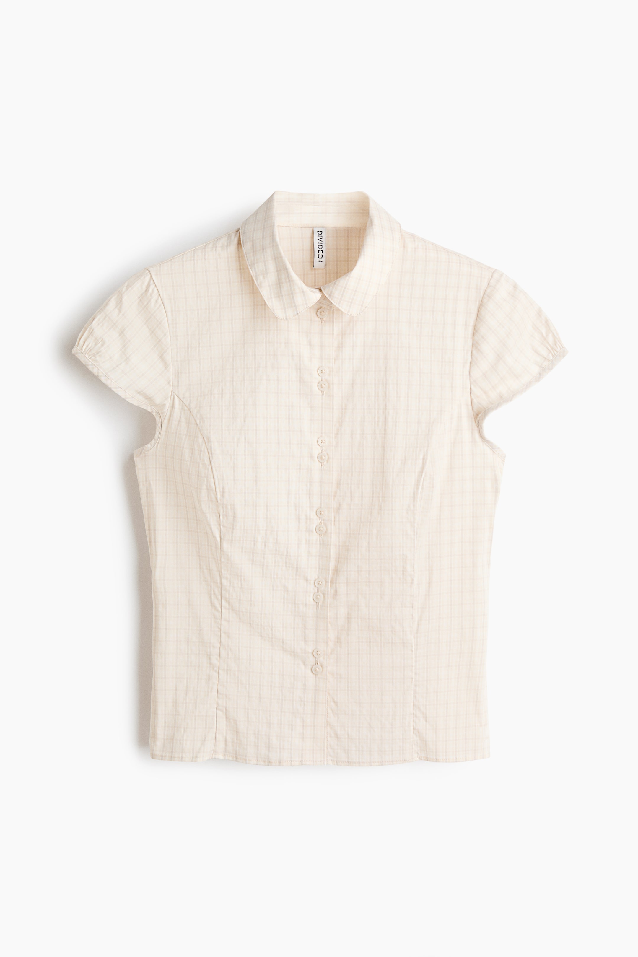 View larger image: A cream-colored, short-sleeved blouse is shown from the front, highlighting a subtle grid plaid pattern. It features a rounded collar, a button-front placket, puffed cap sleeves, and vertical princess seams that create a tailored fit.
