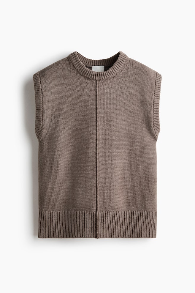 A taupe knitted vest is displaying its front, featuring a ribbed crew neck, ribbed armholes, and a ribbed hem. A distinct vertical seam is running down the center front of the vest. - 1