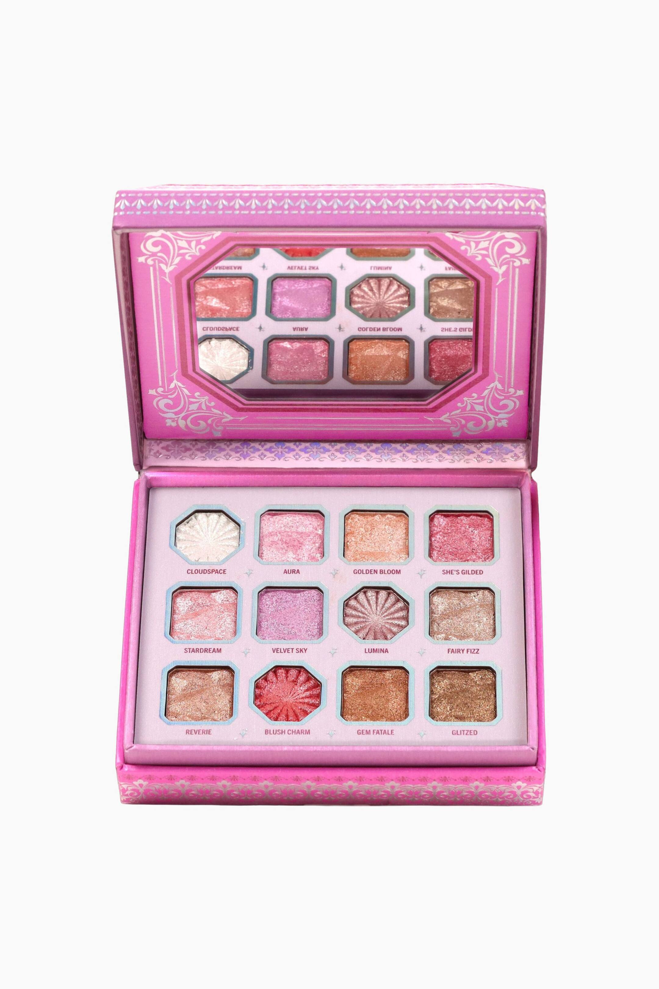 Se større billede: Lumina Vault Eyeshadow Palette står åbent og vendt forover og fremviser tolv skinnende og metalliske øjenskyggepander i nuancer af pink, guld, bronze og lilla. Det øverste låg har et ottekantet spejl, der reflekterer panderne, mens den pink emballage er udsmykket med ornamentale sølvfarvede dekorative mønstre.