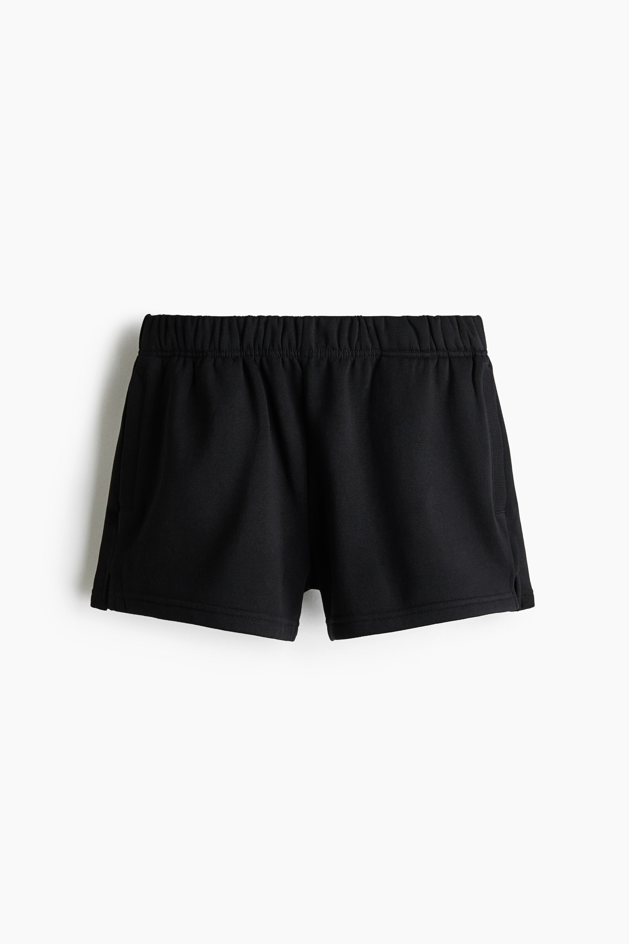 View larger image: Black shorts in sweatshirt fabric are showcased from the front, featuring an elasticated waistband, welt side pockets, and small slits at the hems.