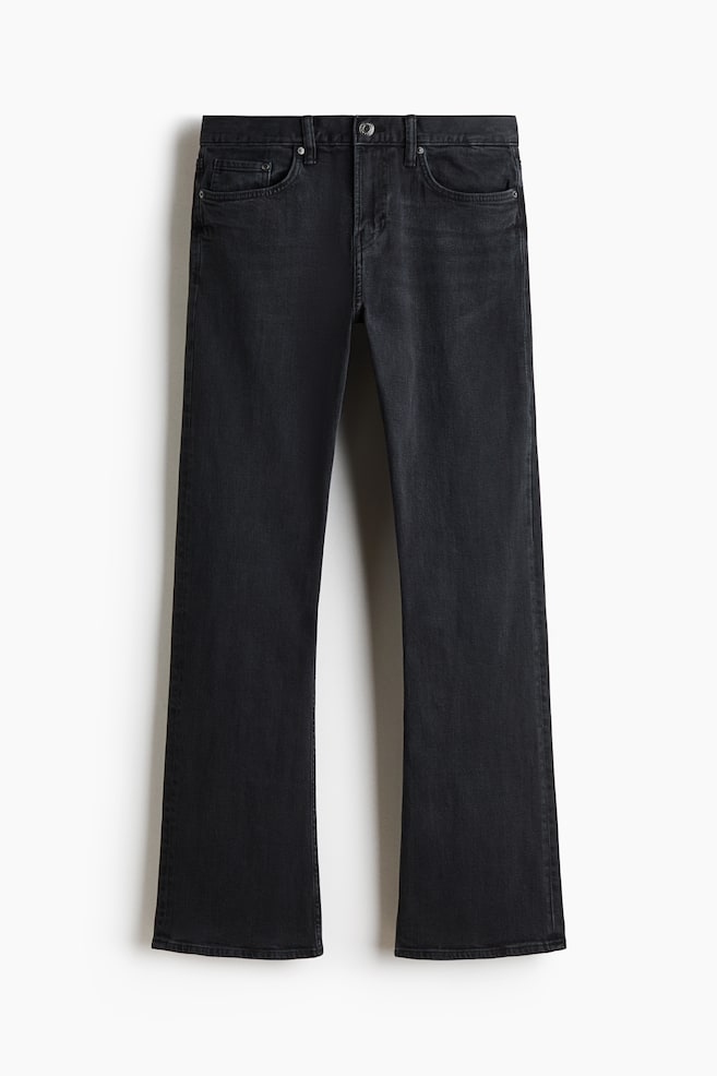 A pair of faded black jeans is shown from the front, featuring a classic five-pocket design with a button fastening and belt loops at the waistband. The jeans have a slim fit through the thigh and flare slightly at the hem. - 1