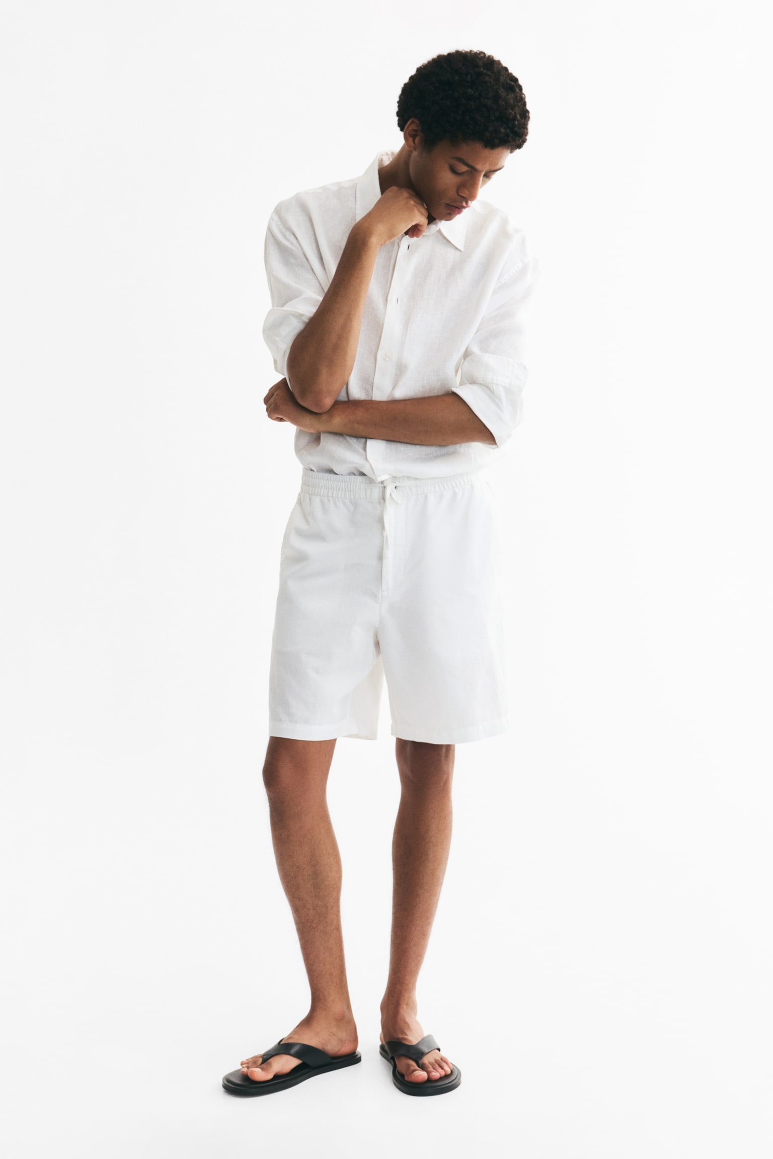 Quần short màu trắng được làm từ chất liệu pha trộn giữa cotton và linen có kết cấu, được giới thiệu từ phía trước, với phần eo co giãn có dây rút và nút cài, cùng với túi may dọc hai bên. - 1