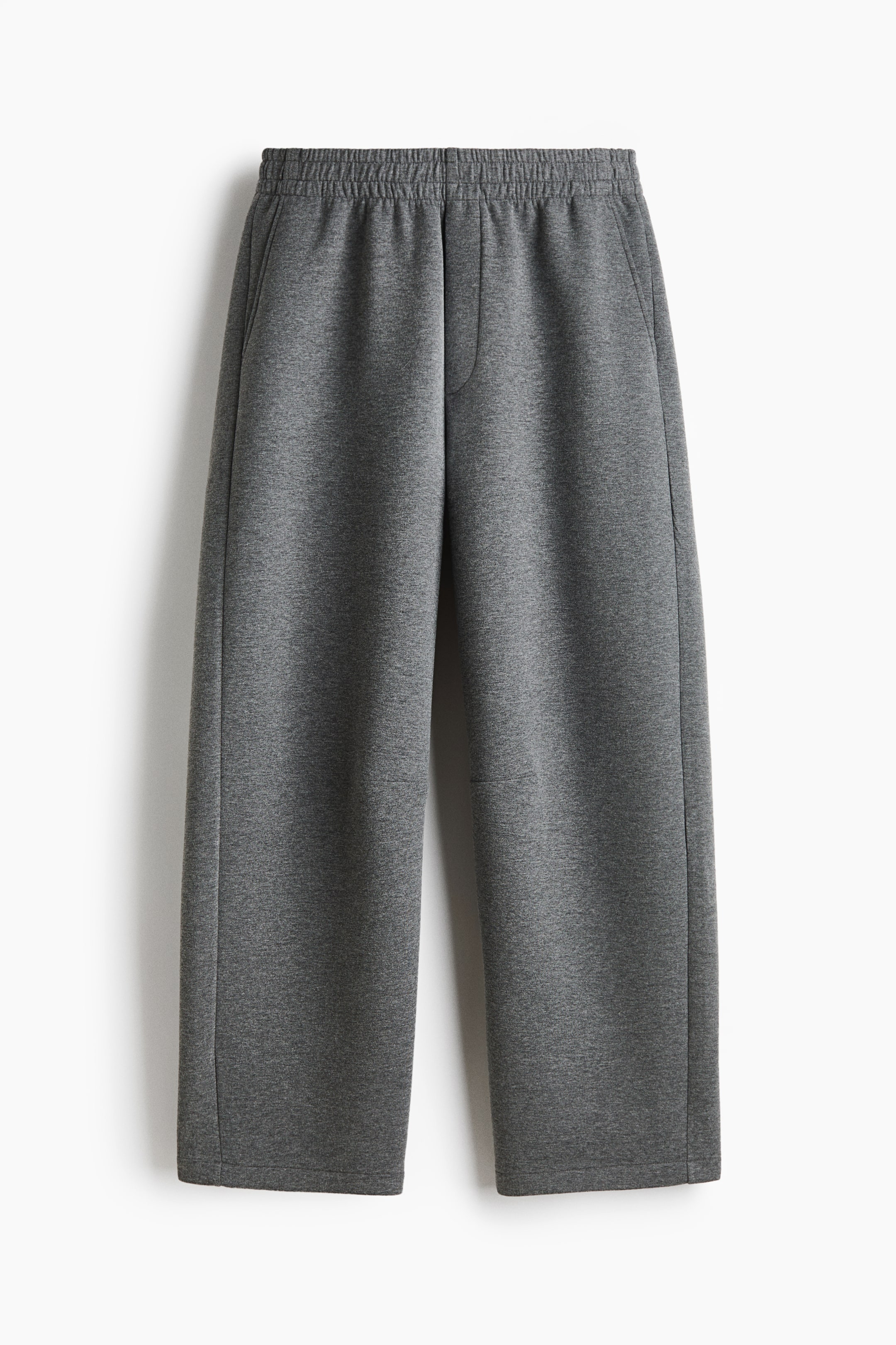 View larger image: These grey wide-leg trousers are shown from the front, featuring an elasticated gathered waistband, side slip pockets, and a mock fly seam. The trousers fall in a relaxed, straight-leg silhouette with clean, open hems.
