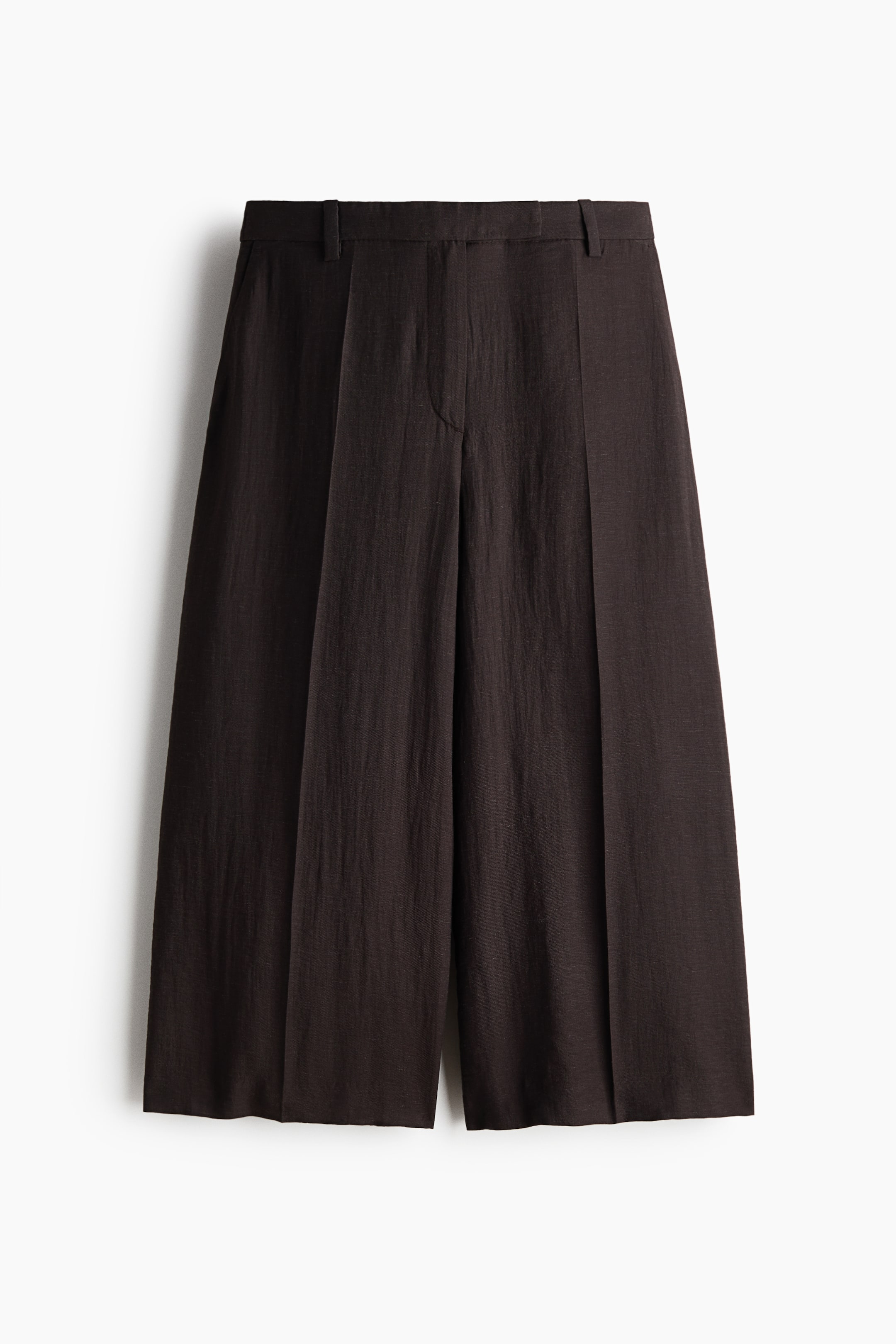 Visualizza l'immagine ingrandita: Pantaloni cropped a gamba larga color marrone scuro, visibili frontalmente, con una cintura piatta con passanti per cintura e pieghe verticali prominenti lungo la parte anteriore di ciascuna gamba.