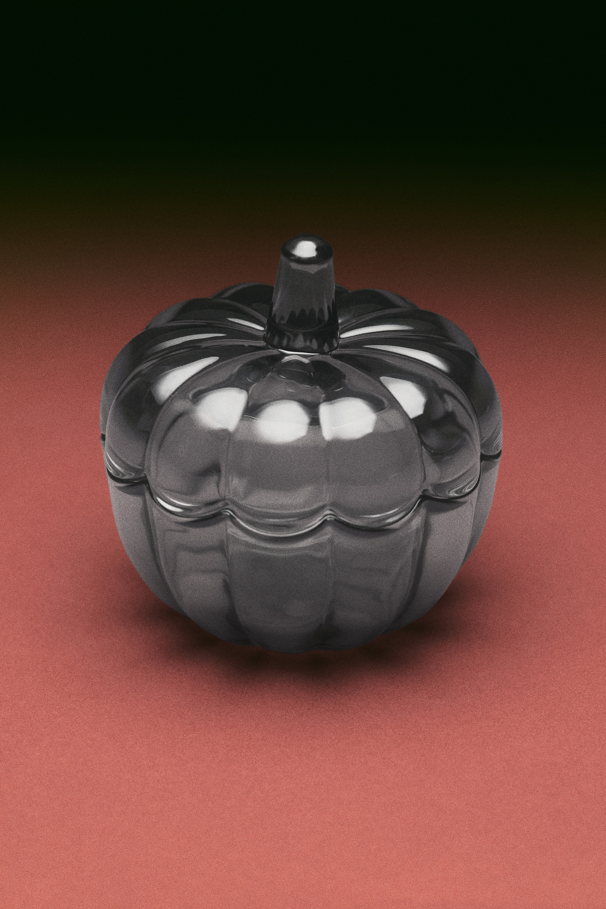 A small, translucent dark grey glass jar with a lid is displaying a pumpkin design, showing ribbed sections forming its body and a stem-like handle on the lid.