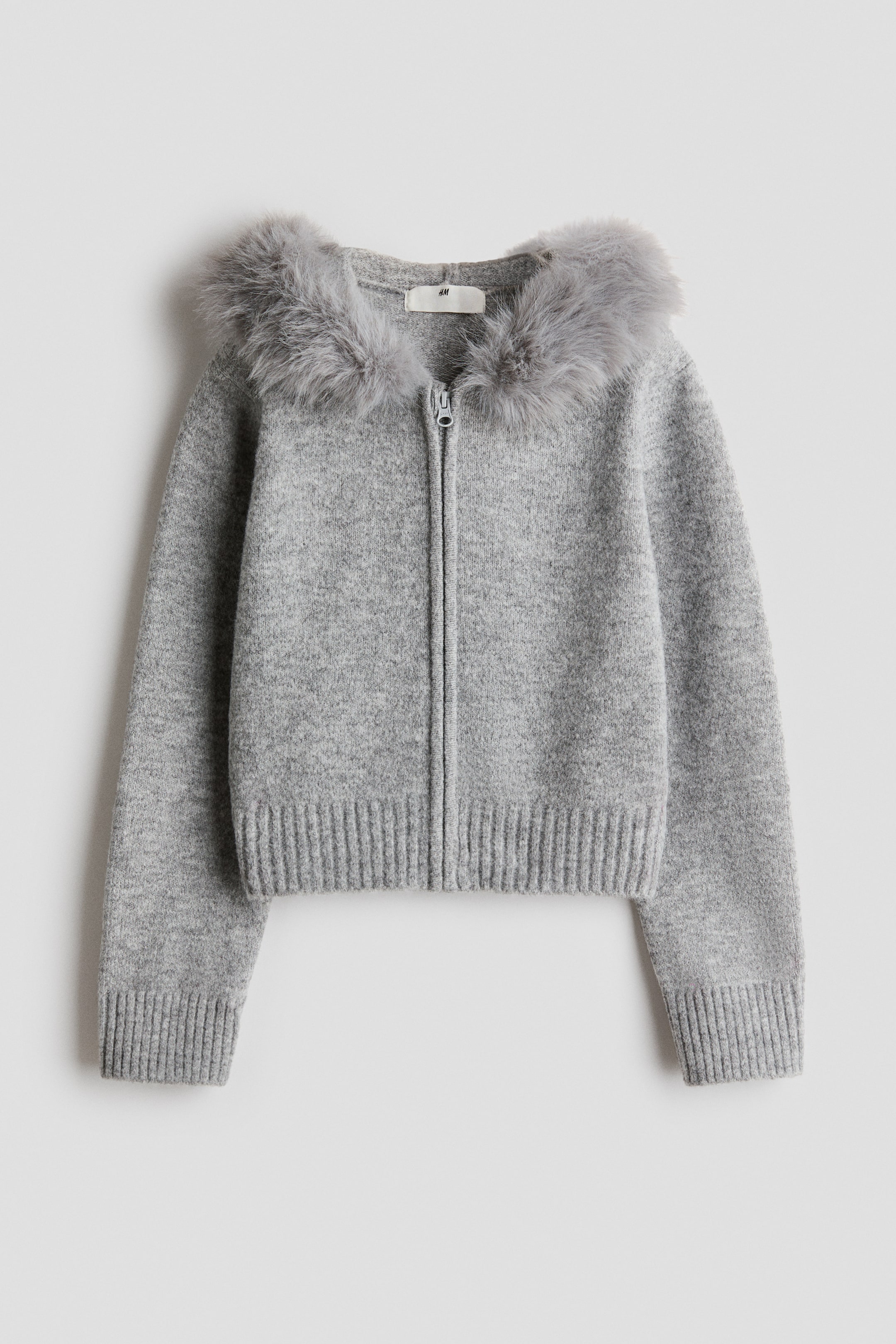 View larger image: A grey knitted cardigan is laid flat and facing forward, featuring a full-length front zip closure, grey faux fur trim around the neckline, long sleeves with ribbed cuffs, and a ribbed hem.