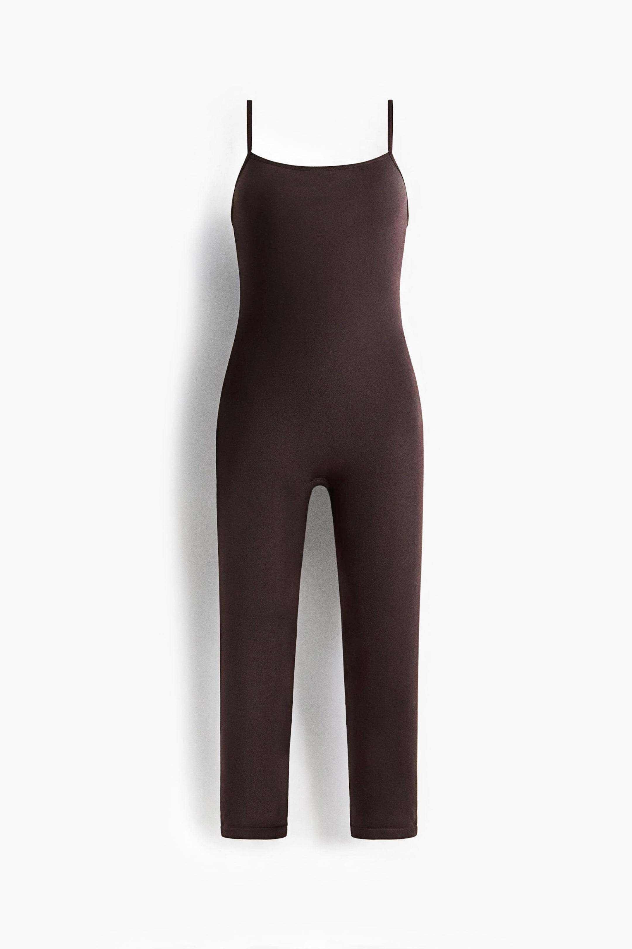 Grotere afbeelding bekijken: Een donkerbruine unitard van stretchjersey wordt van voren getoond, met een rechte halslijn en smalle, verstelbare schouderbandjes. Het nauwsluitende eendelige model loopt door tot een cropped lengte en heeft een strakke, naadloze afwerking.