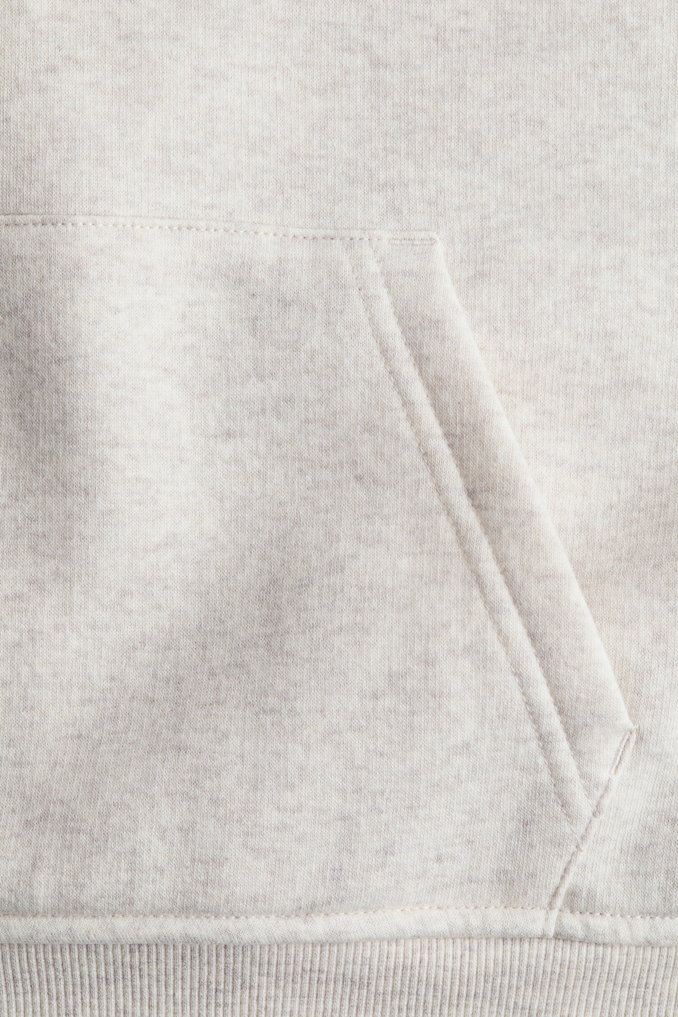 Größeres Bild ansehen: Ein Hoodie mit Kängurutasche auf der Vorderseite, gefertigt aus einem leichten, melierten Sweatshirtstoff, mit einem gerippten Saum, der entlang der unteren Kante sichtbar ist.