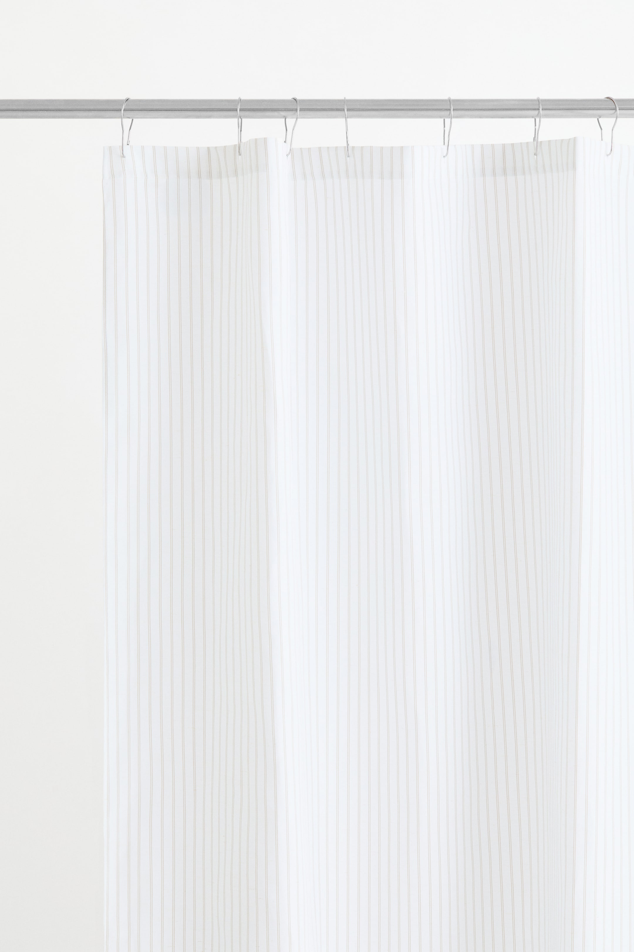 View larger image: A shower curtain showcasing a linen-blend weave with a subtle striped pattern, featuring thin, light-coloured vertical lines. Metal eyelets are visible at the top, from which shower curtain rings are suspending the curtain.