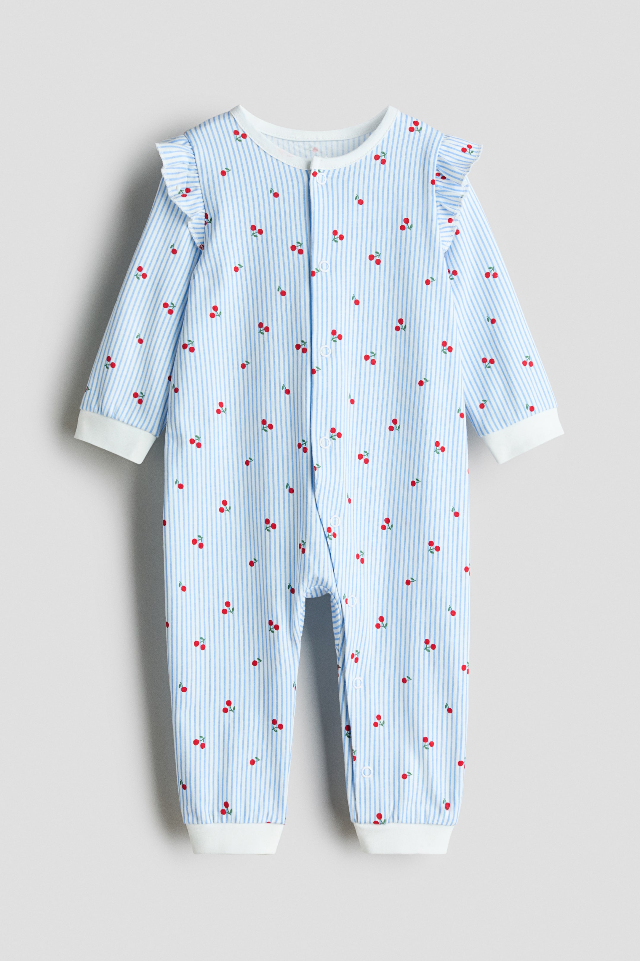 이미지 확대 보기: 아기 잠옷은 앞면을 보여주고 있으며, 밝은 파란색과 흰색의 세로 줄무늬 패턴에 작은 빨간 체리 프린트가 특징입니다. 긴 소매에 어깨 부분이 주름 잡힌 흰색 커프스와 긴 다리에 흰색 커프스 밑단이 디자인되어 있으며, 흰색 프레스 스터드가 앞면과 다리 부분을 따라 내려가고 있습니다.