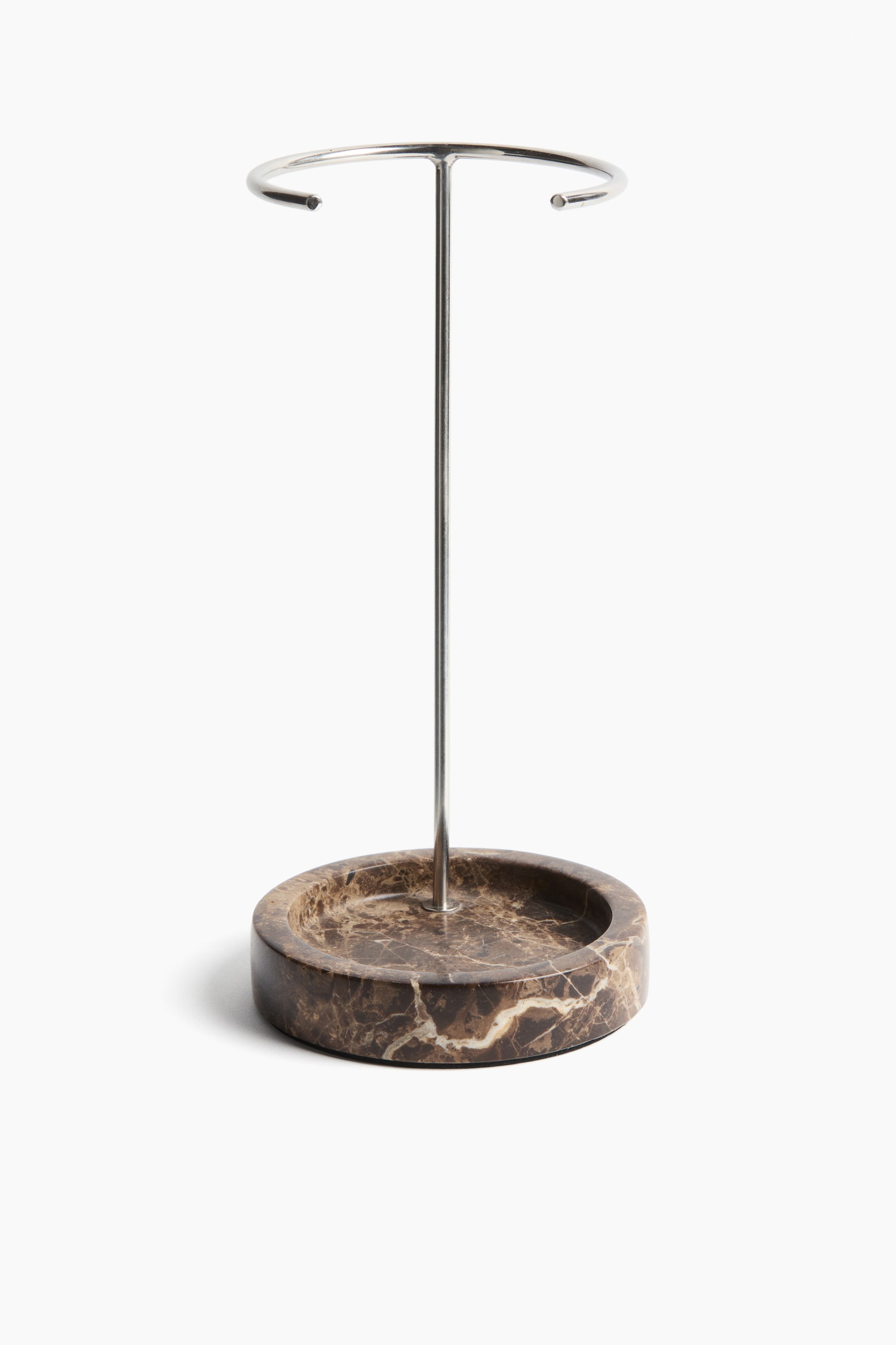 View larger image: The display stand showcases a round, brown marble base adorned with elegant white veining. From this base, a sleek silver-colored metallic rod ascends, culminating in a circular metallic ring at the top.