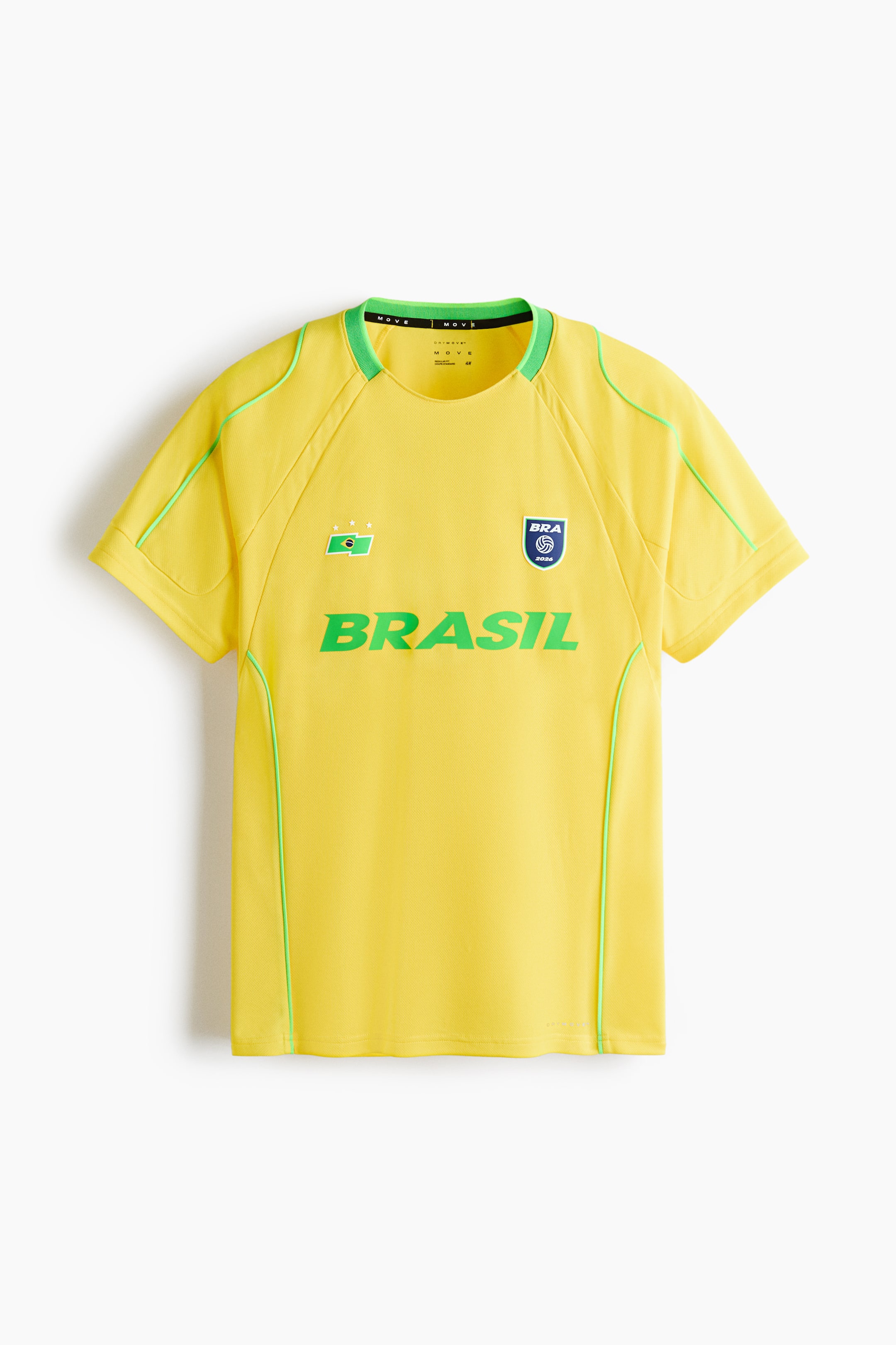 Voir une image plus grande: Un t-shirt jaune est présenté de face, avec un col rond côtelé vert, des manches courtes raglan et des passepoils verts soulignant les coutures des épaules et les côtés. Le devant affiche un emblème rectangulaire vert avec une forme blanche et trois étoiles blanches sur la poitrine gauche, un emblème en forme de bouclier bleu avec le texte "BRA" et un graphique de volleyball sur la poitrine droite, ainsi qu'un grand texte vert "BRASIL" au centre.
