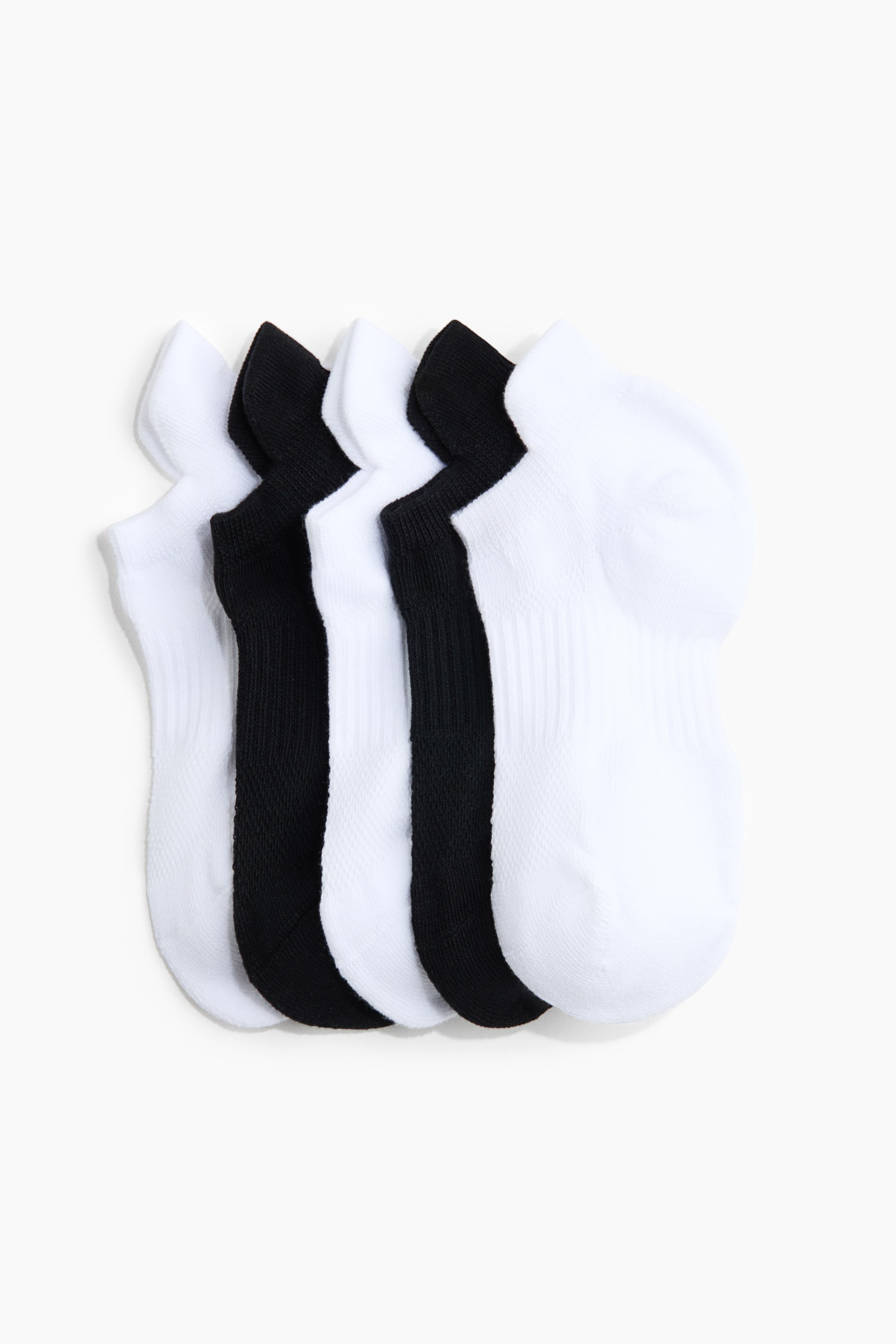 Visa större bild: Fem par ankelsockor staplas i ett växelvis svart och vitt mönster. Varje socka har ribbade muddar och texturerade fotpaneler.