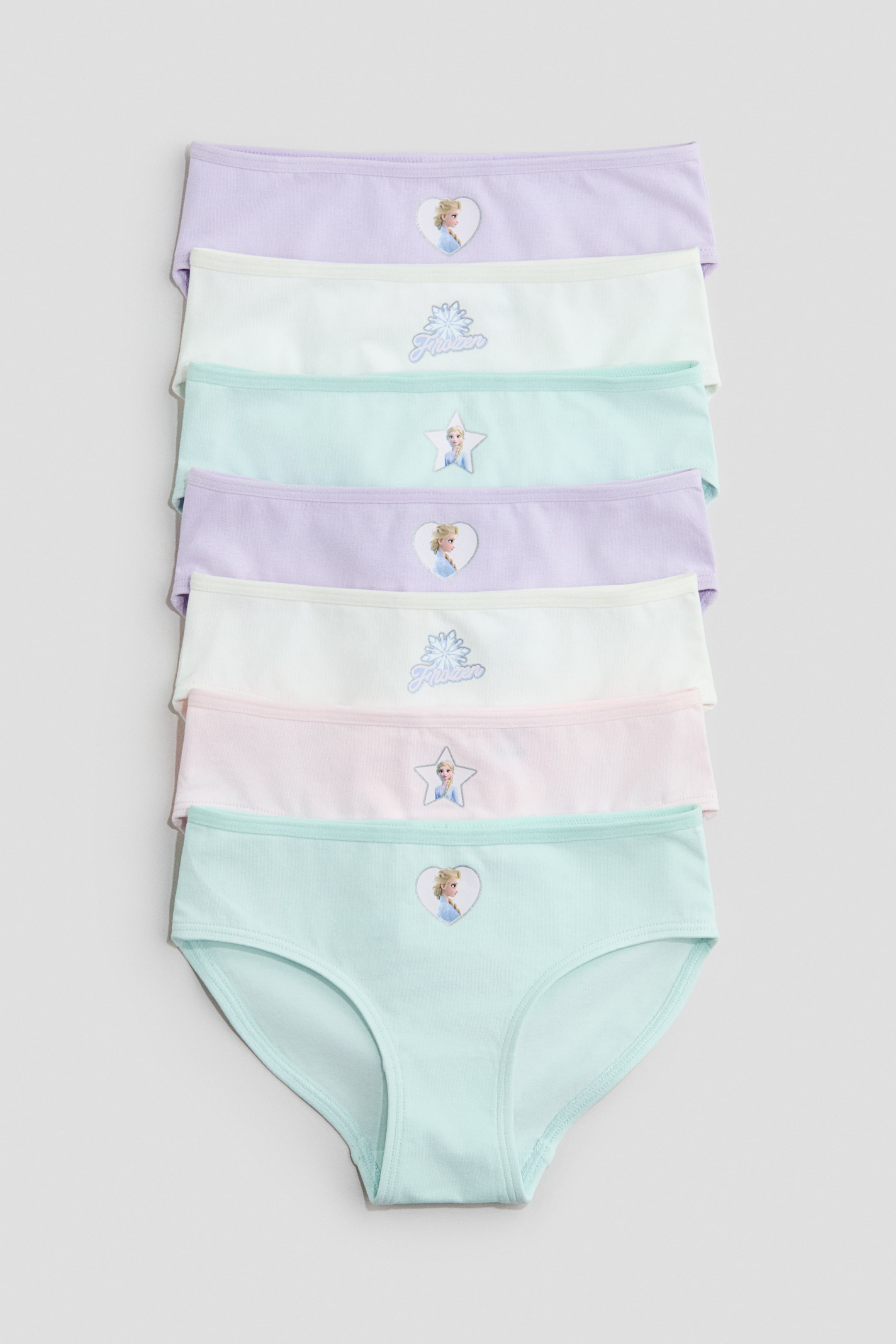 Näytä suurempi kuva: Painetusta puuvillatrikoosta valmistetut alushousut esitellään seitsemän parin pinona, jotka levittäytyvät etupuoli näkyvissä. Alushousut ovat pastellisävyissä, kuten laventeli, valkoinen, mintunvihreä ja vaaleanpunainen, ja jokaisessa on etupuolella hahmokuvio.