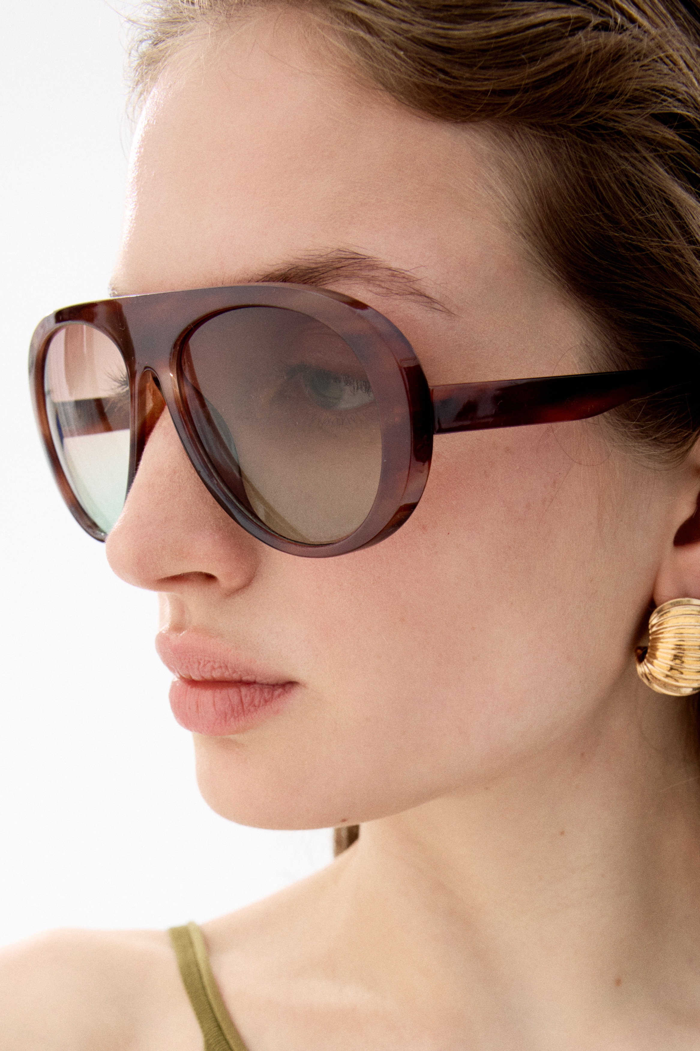 Aviator-style sunglasses are facing front, featuring thick, dark brown plastic frames. Their tinted lenses are displaying a gradient from dark brown to light green, providing UV protection.