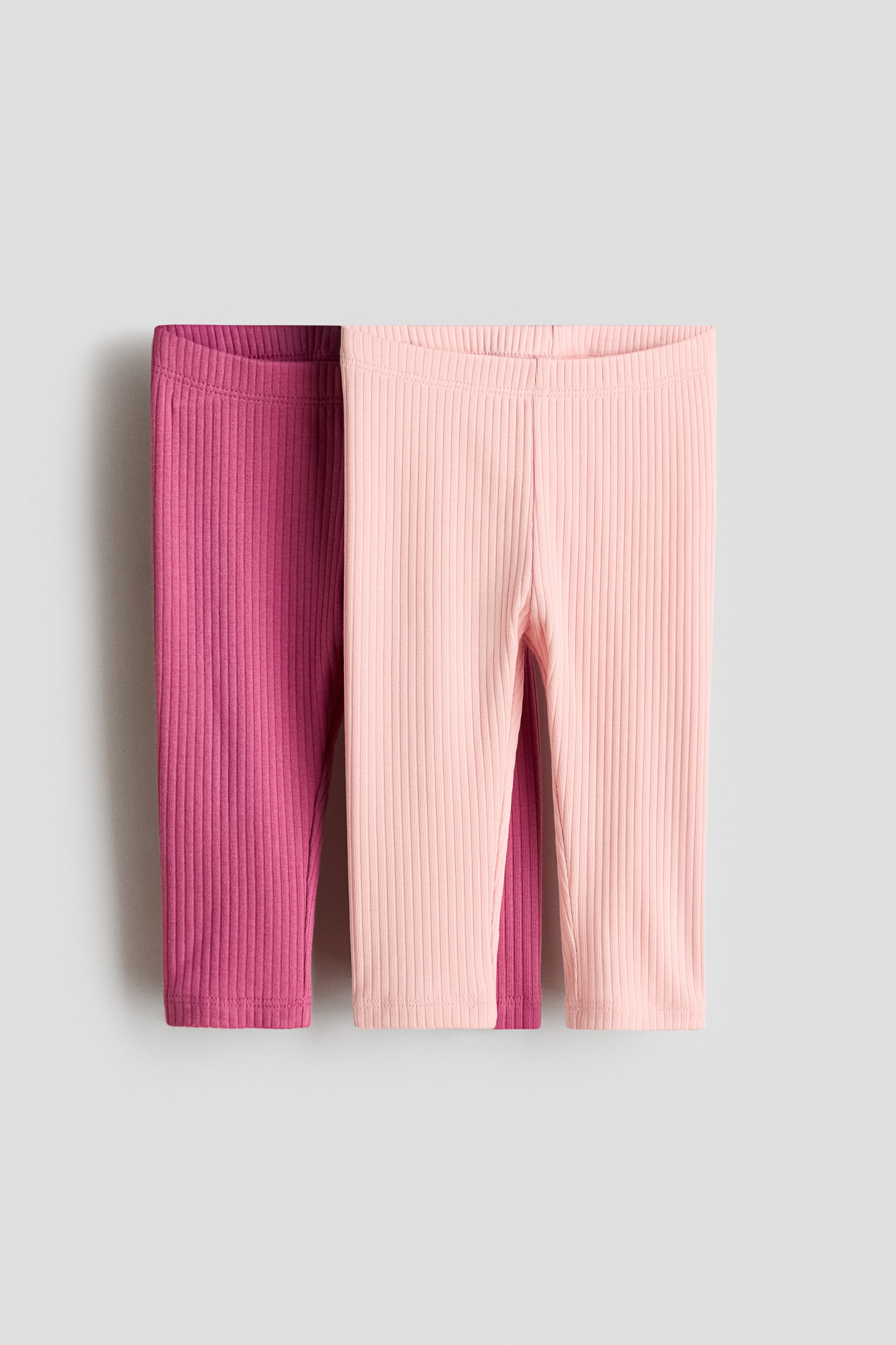 Agrandir l'image: Deux paires de leggings côtelés sont présentées de face, exhibant une texture en maille côtelée verticale. La paire de gauche affiche une couleur magenta profond, tandis que la paire de droite présente une teinte rose clair, toutes deux dotées d'une taille élastiquée et d'une coupe droite.
