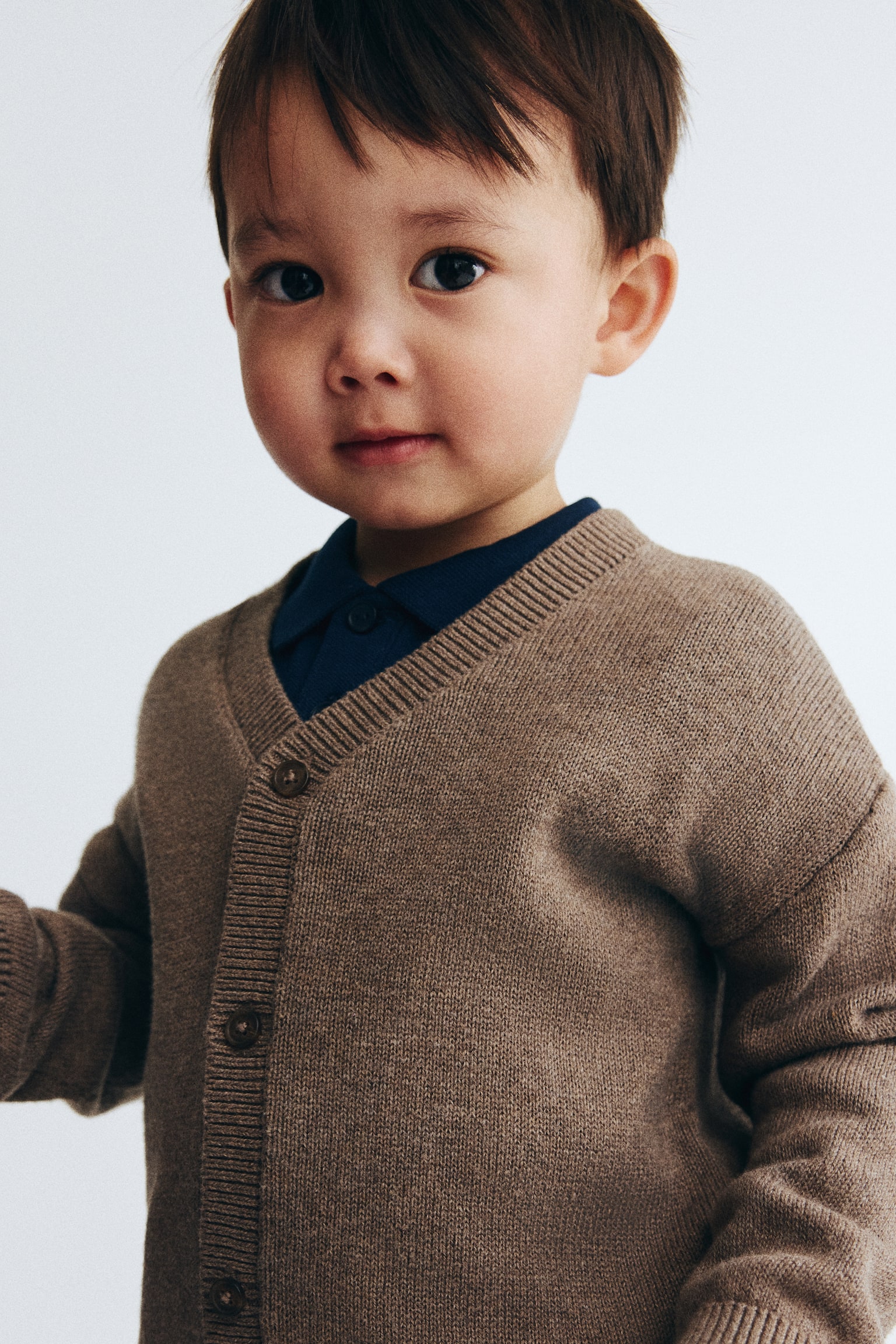 A heathered brown knit cardigan is hanging flat, presenting its front view, featuring a V-neckline, a button-front closure with five brown buttons, ribbed cuffs, and a ribbed hem. - 1