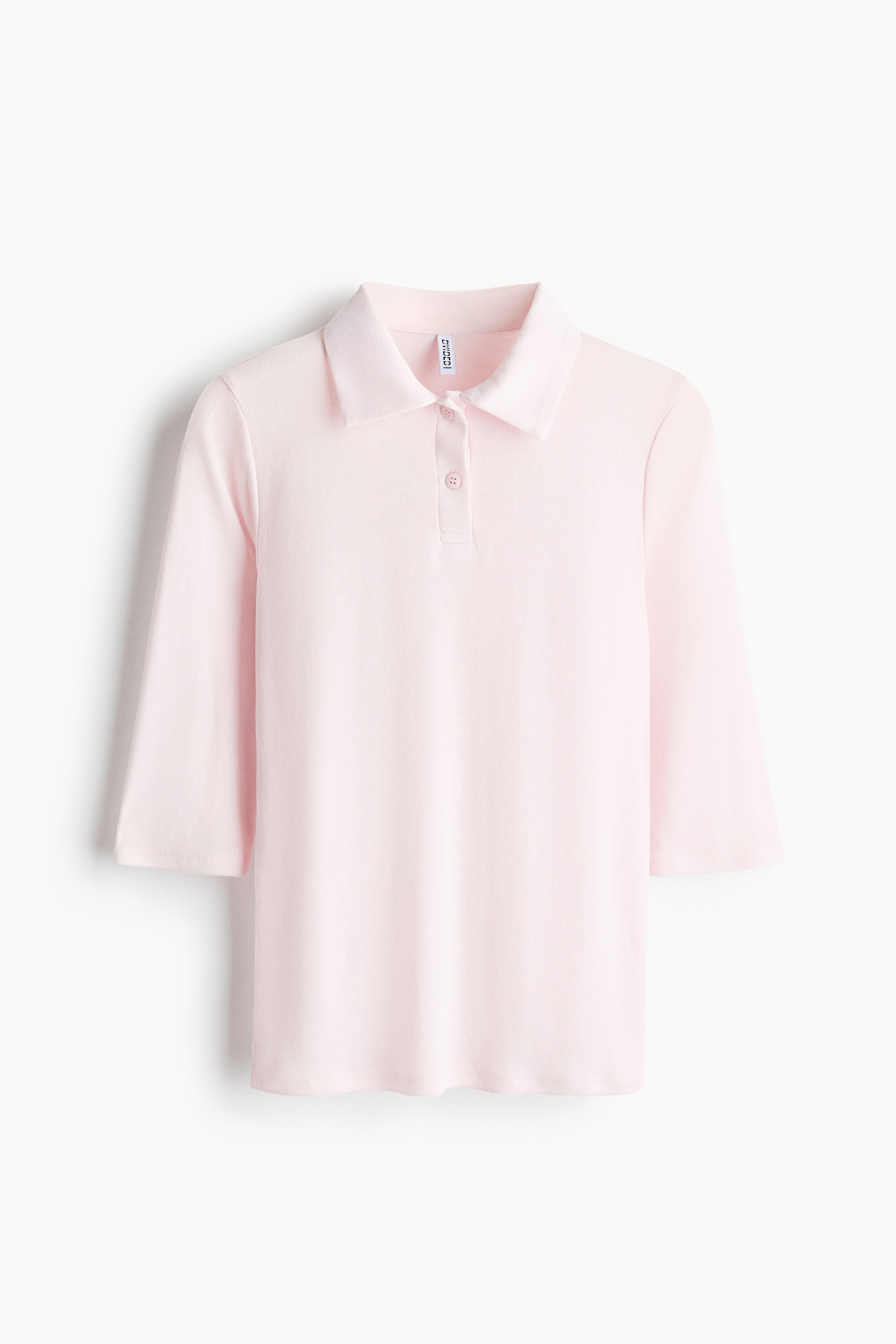 A light pink polo shirt in a fine ribbed jersey is being worn by the model, featuring a collar, a button placket, 3/4-length sleeves, and a straight hem. The shirt is styled with light-wash denim jeans and a pink and grey striped knit sweater tied around the waist.
