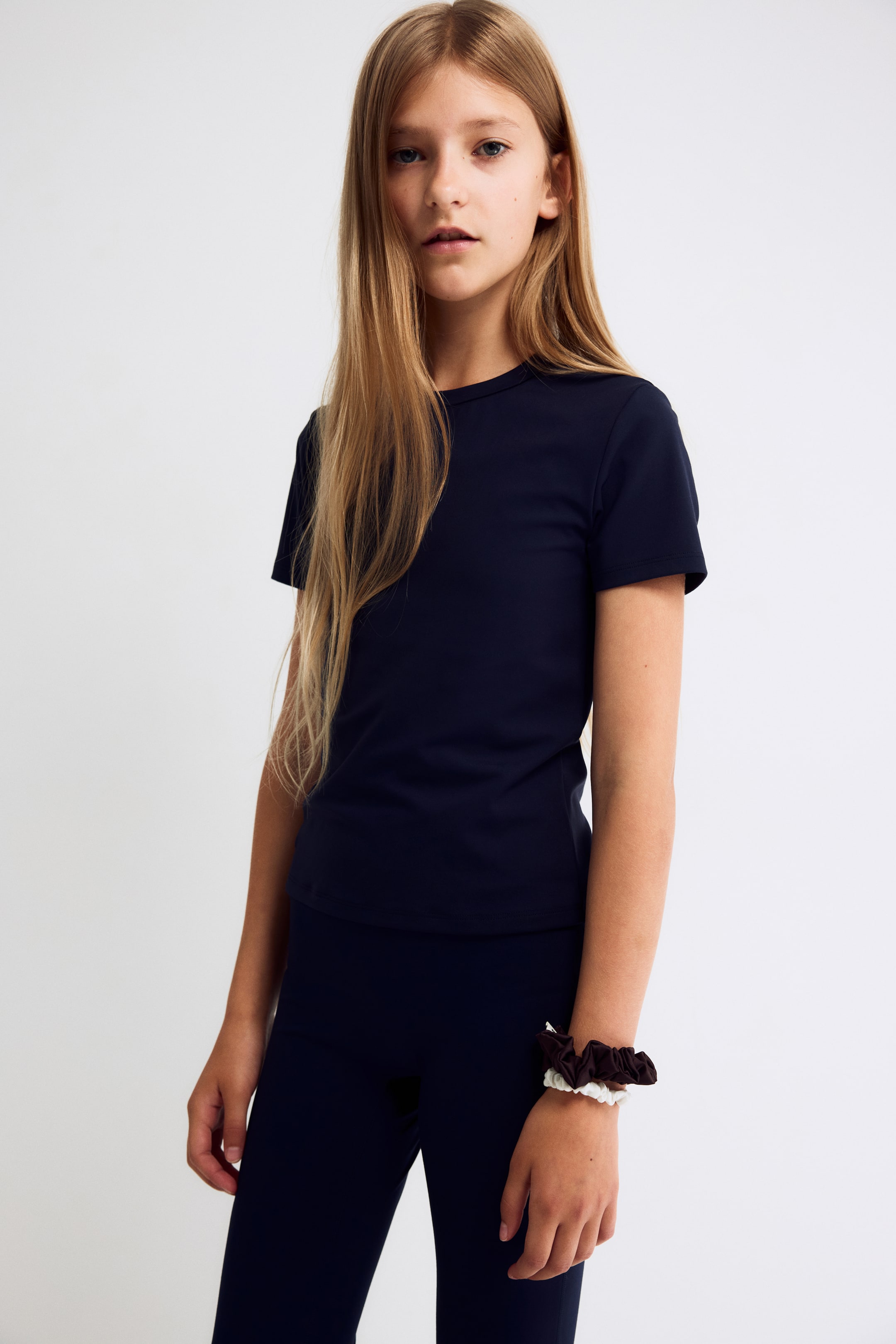 View larger image: A dark navy blue short-sleeved T-shirt and matching leggings are displayed from the front, showcasing a fitted, minimalist style. The crew-neck T-shirt features a straight hem, while the coordinating leggings provide a snug, streamlined fit.